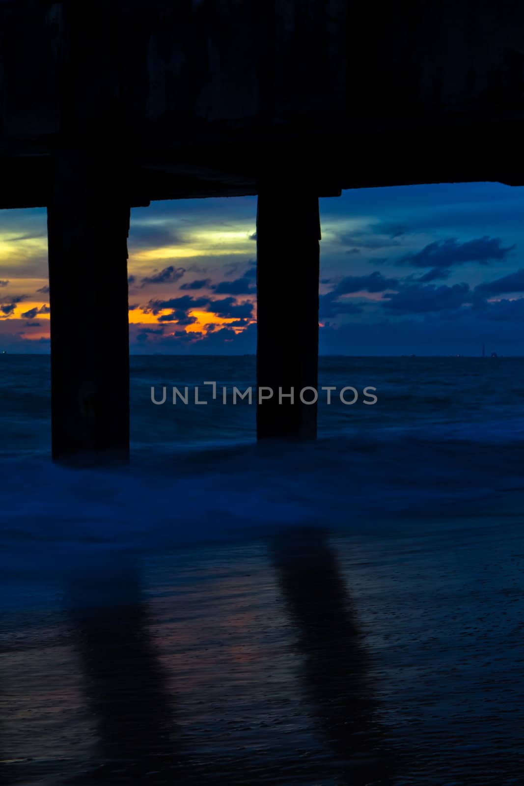 Pillars of the bridge on the beach. At sunset.