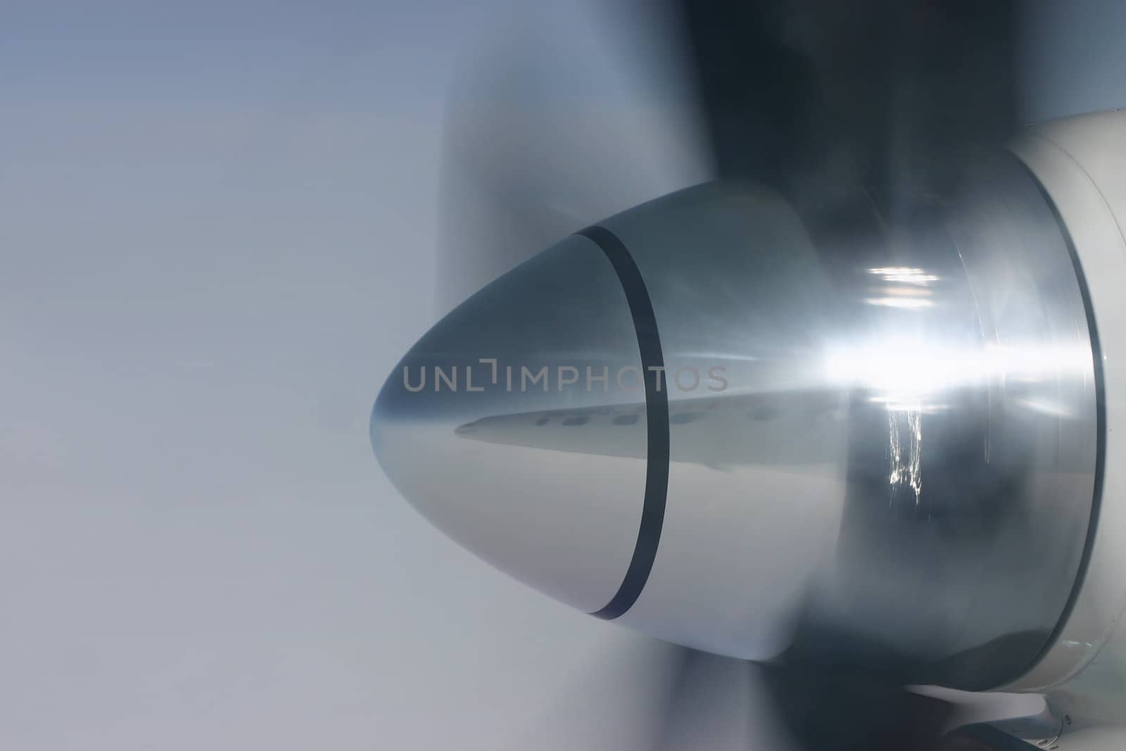 Spinning propeller with a reflection of the airplanes fuselage in the propeller cone.