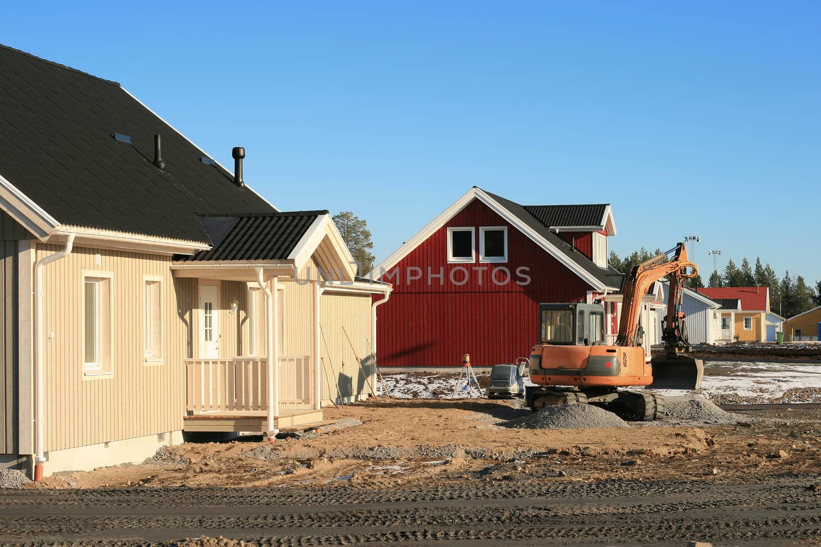 Land preparation with a small excavator around newly built homes.