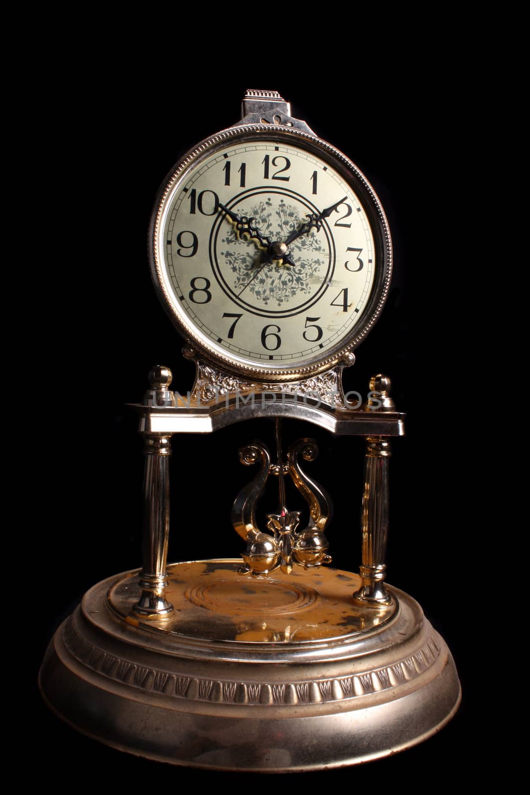 A vintage metallic clock, isolated on black studio background.