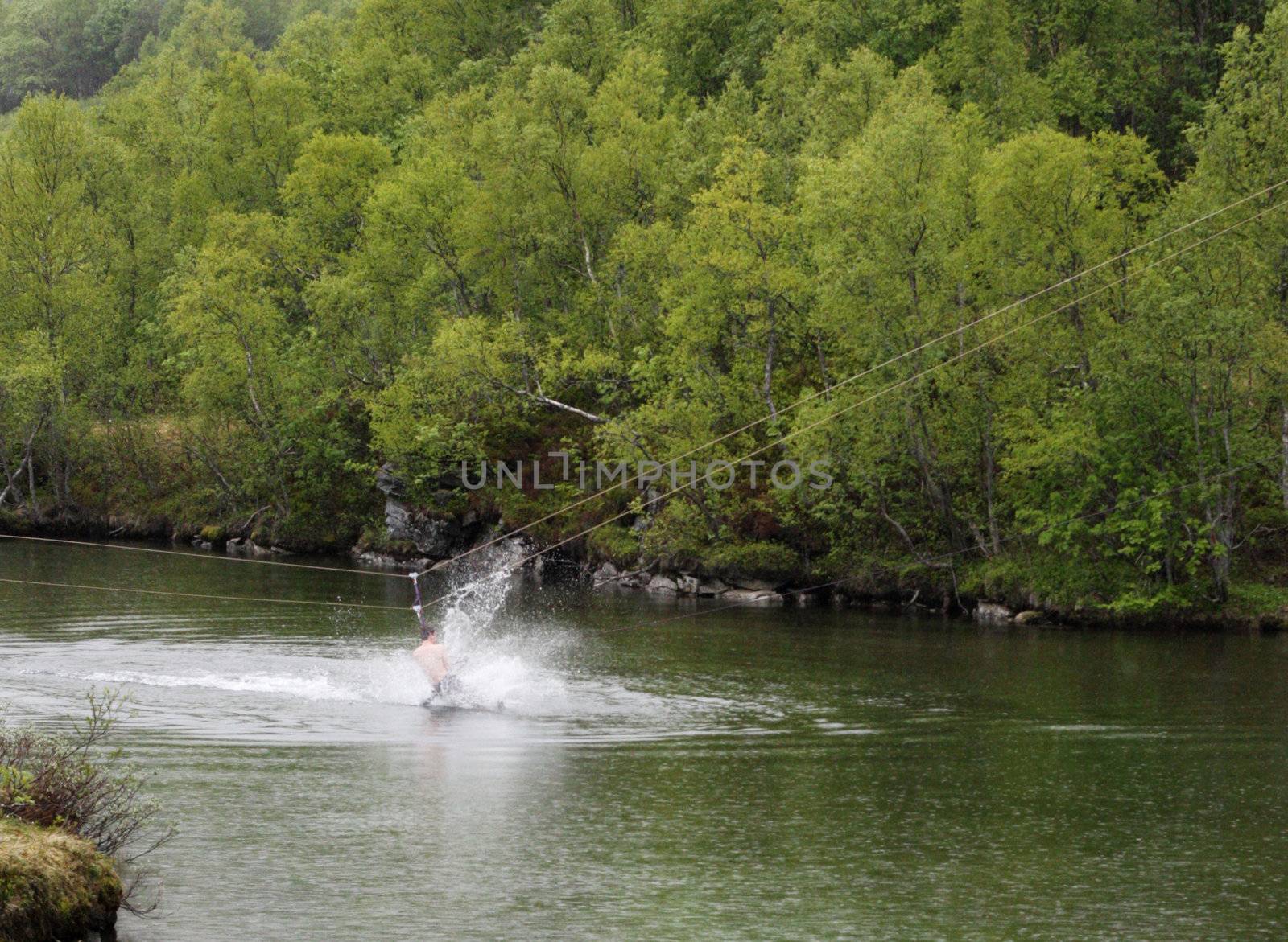 Man rappelling down into a river, getting a bath in the process