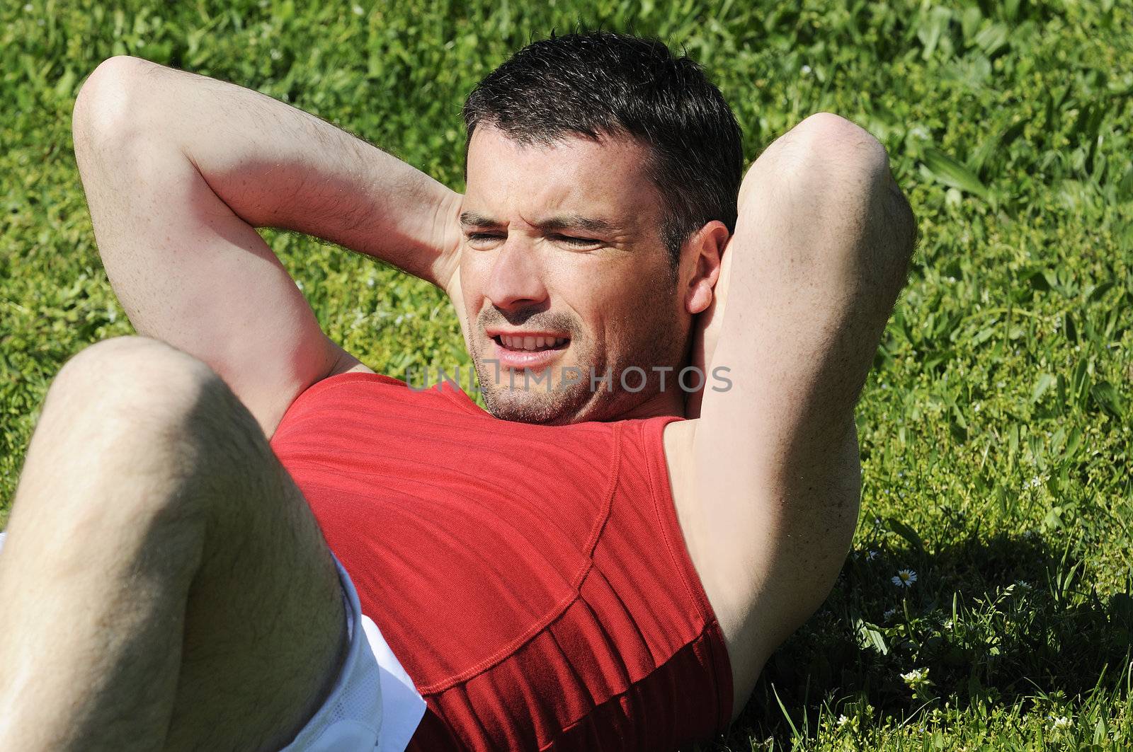 attractive man is doing situps in the fresh grass