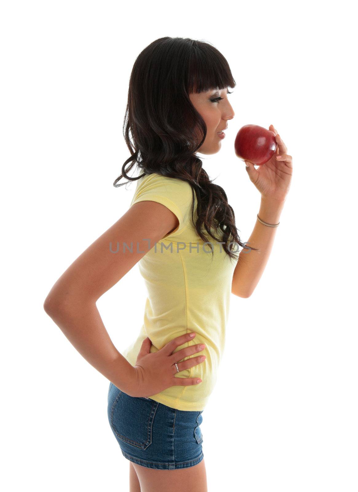 A healthy young woman eating a piece of fruit.  White background.