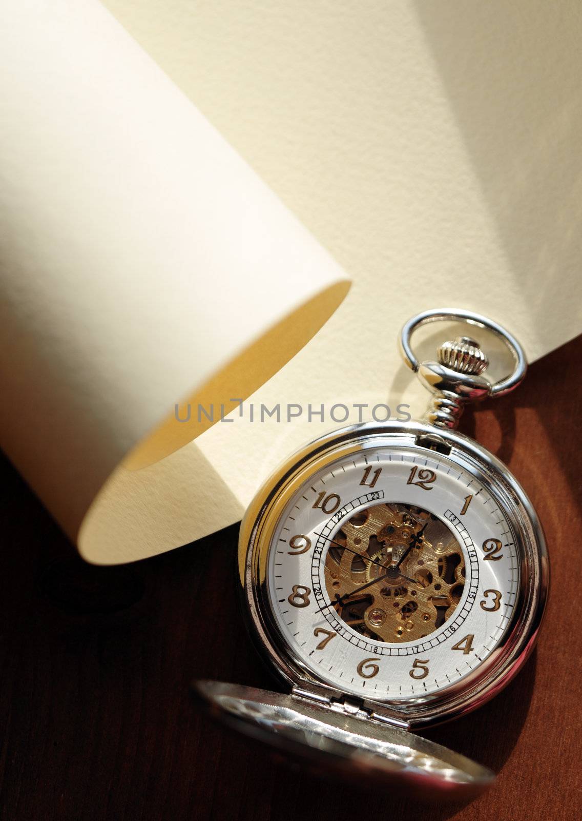 Closeup of nice pocket watch with open lid lying on blank scroll