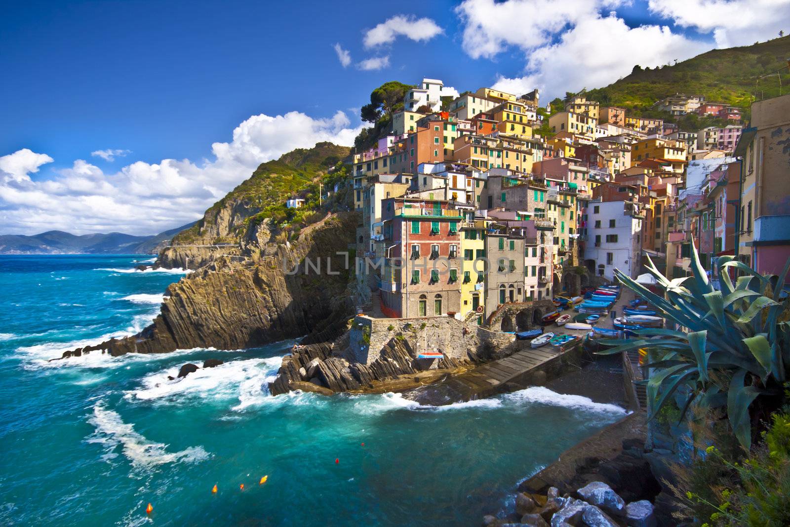 Riomaggiore fisherman village in a dramatic windy weather. Riomaggiore is one of five famous colorful villages of Cinque Terre in Italy, suspended between sea and land on sheer cliffs upon the  turquoise sea.