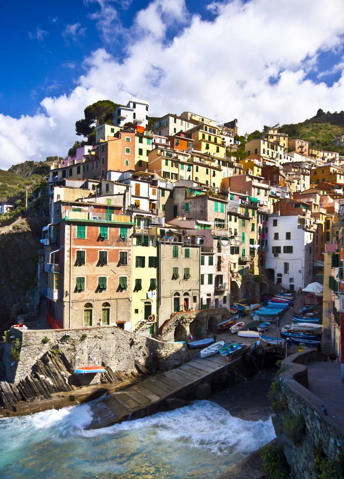 Riomaggiore fisherman village in a dramatic windy weather. Riomaggiore is one of five famous colorful villages of Cinque Terre in Italy, suspended between sea and land on sheer cliffs upon the  turquoise sea.