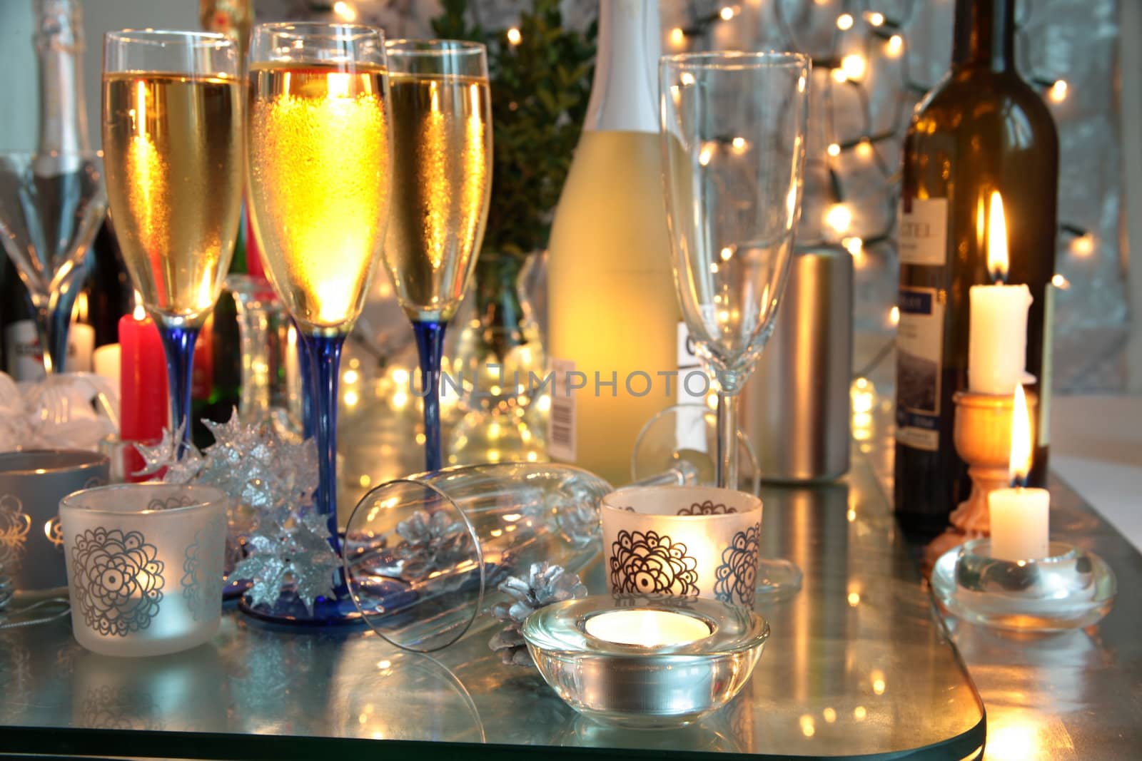 Champagne in glasses,candle lights,bottles and blurred lights on background.