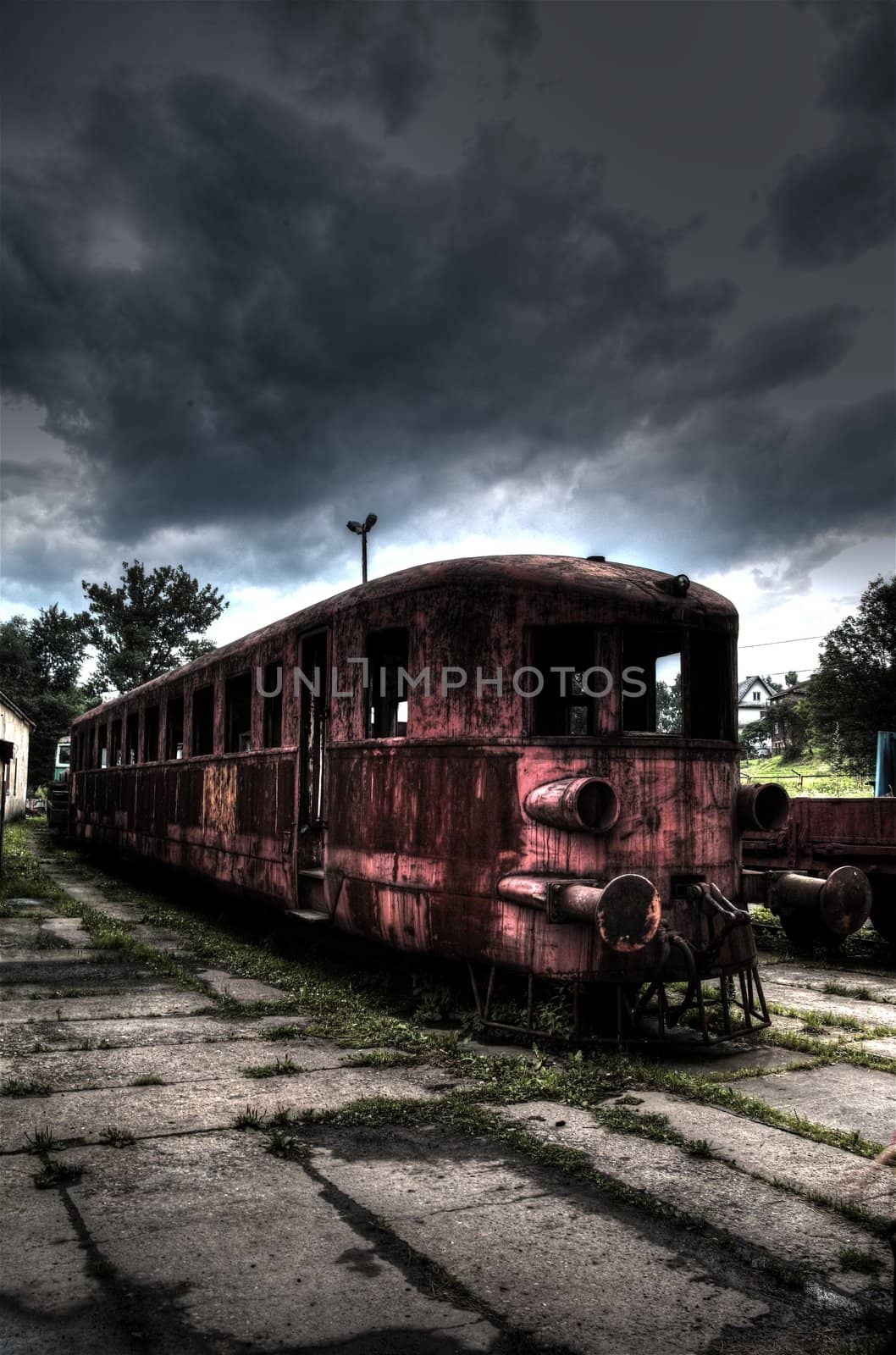 Old rusty and dirty train on background with sky covered by stormy clouds.
