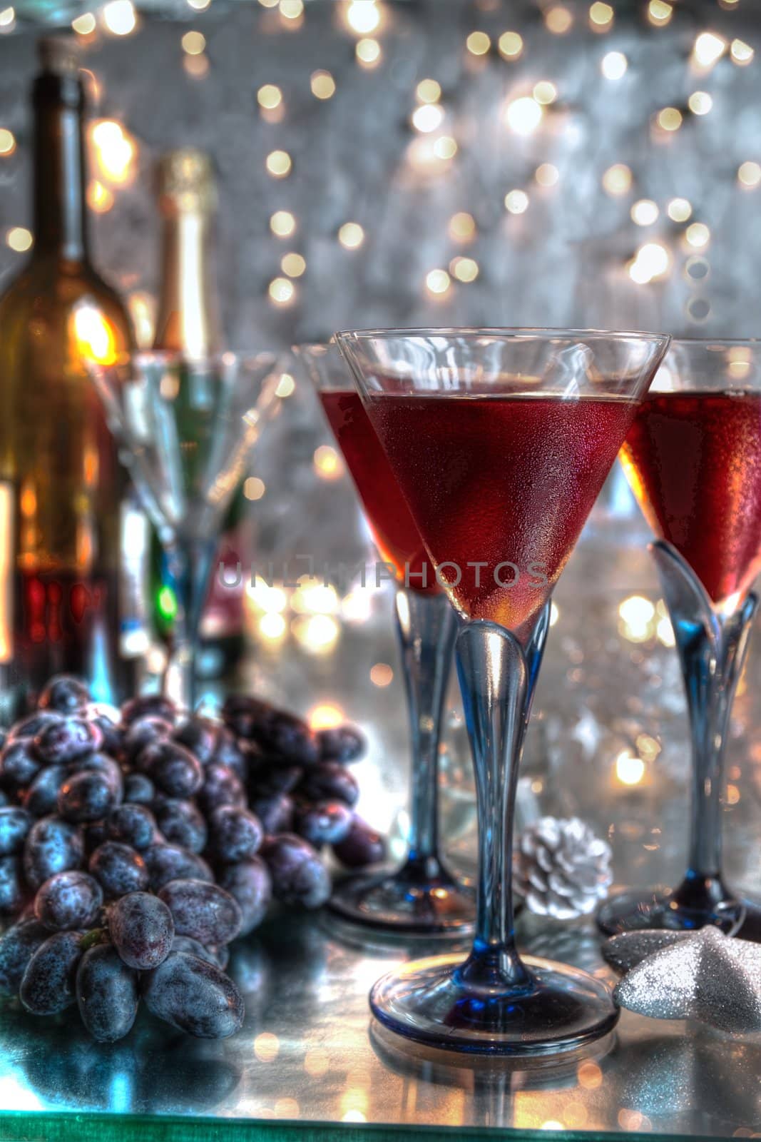 Red wine in glasses,bottles,grapes and blurred lights on silver background.
