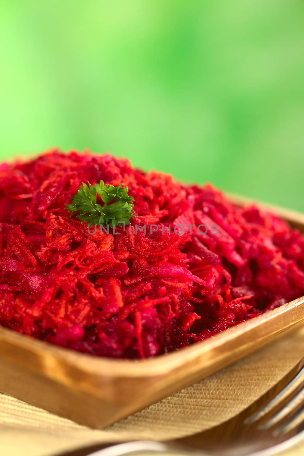 Fresh grated beetroot, carrot and apple salad garnished with a parsley leaf (Selective Focus, Focus on the front of the parsley leaf)