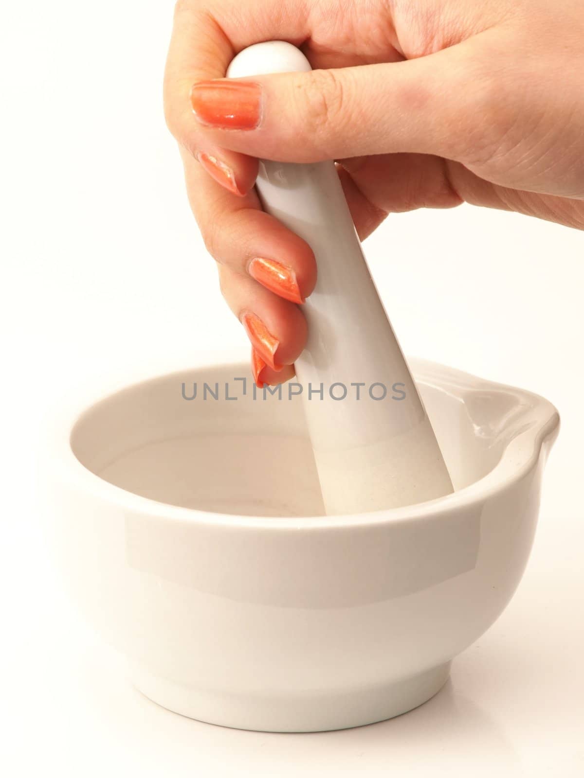 Woman with orange manicure, operating a white marble mortar isolated towards white