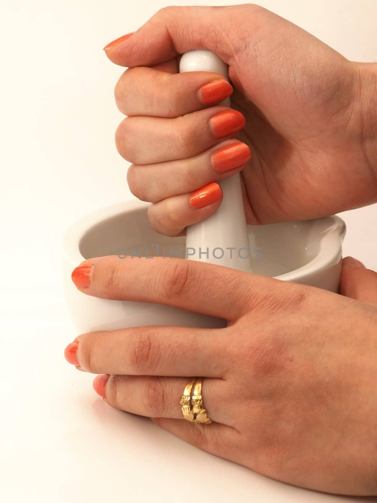Woman with orange manicure, operating a white marble mortar isolated towards white