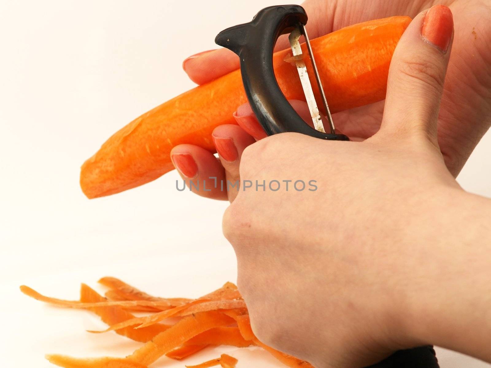 Woman pealing a carrot with matching nail polish, isolated towards white background