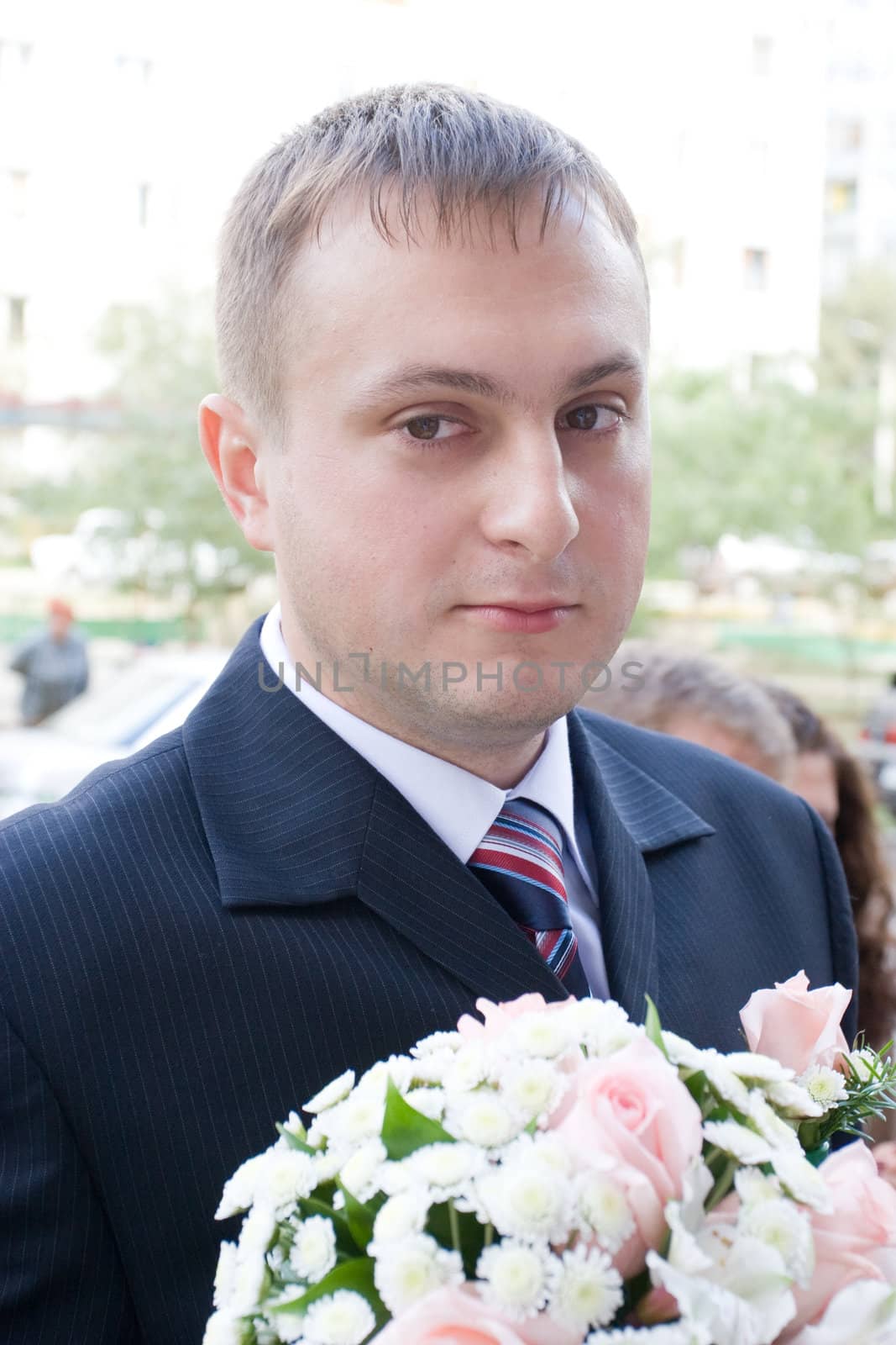 well-dressed groom with a rose bouquet