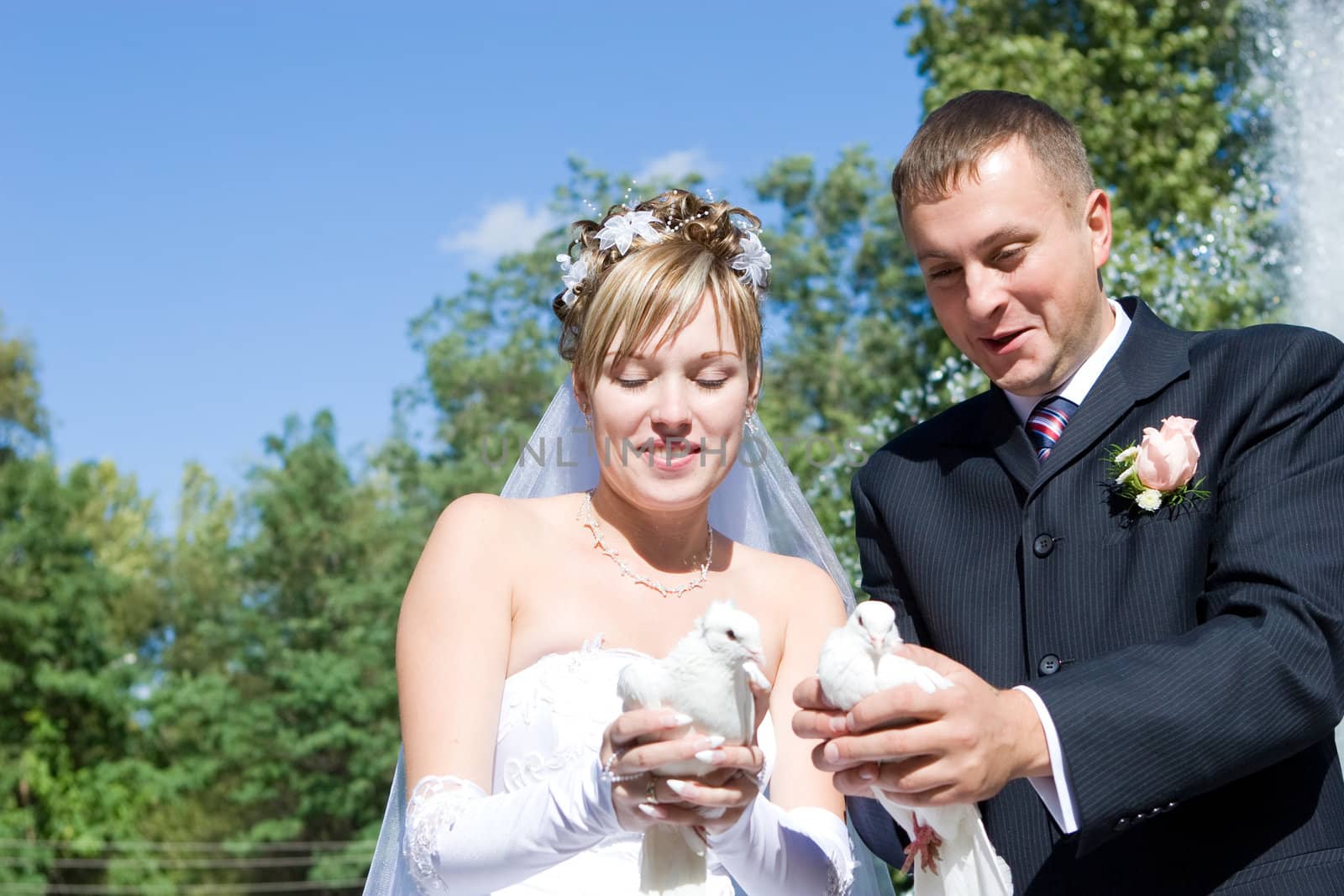 bride and groom with white pigeons in hands