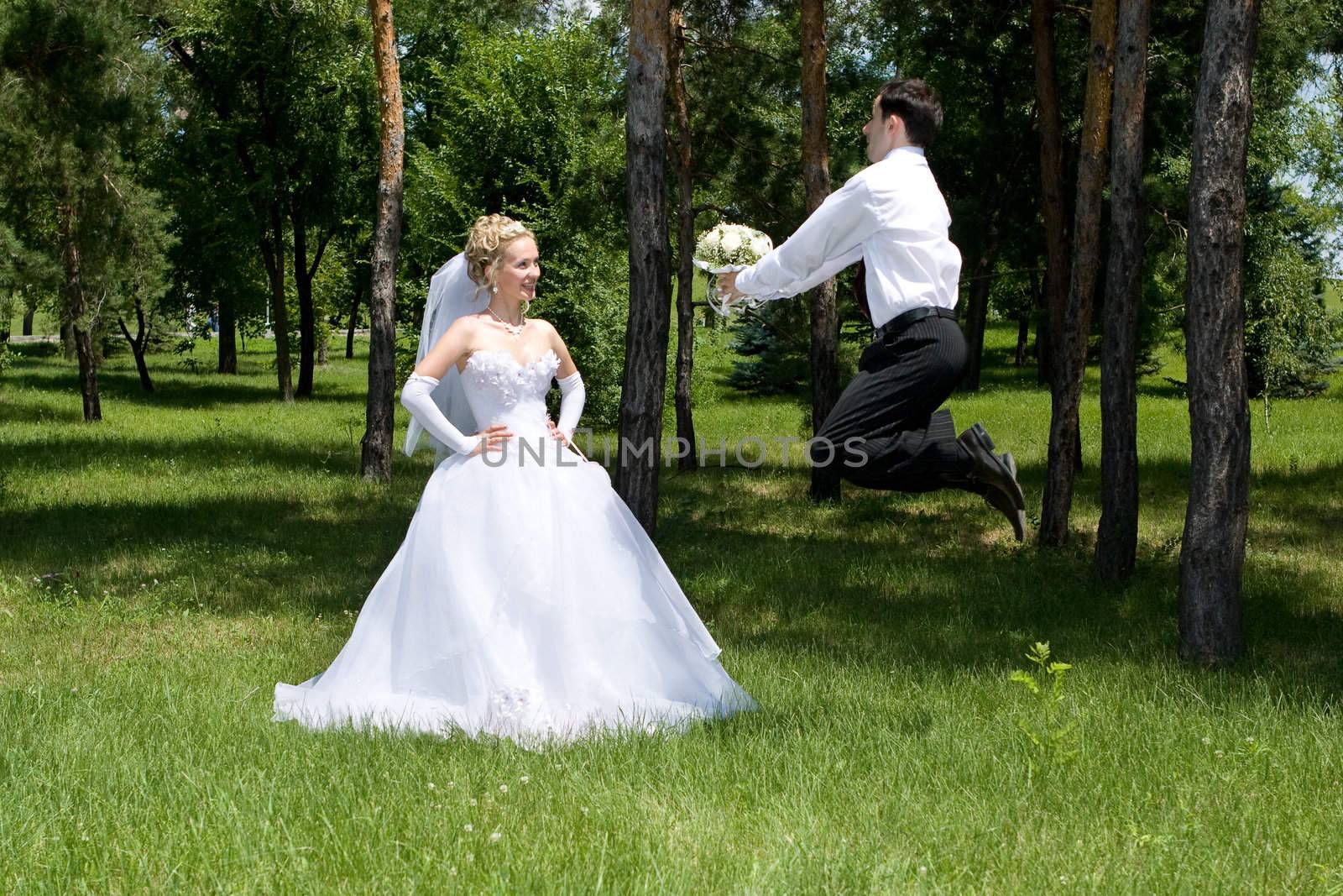 groom with a wlower bouquet jumps  near the bride