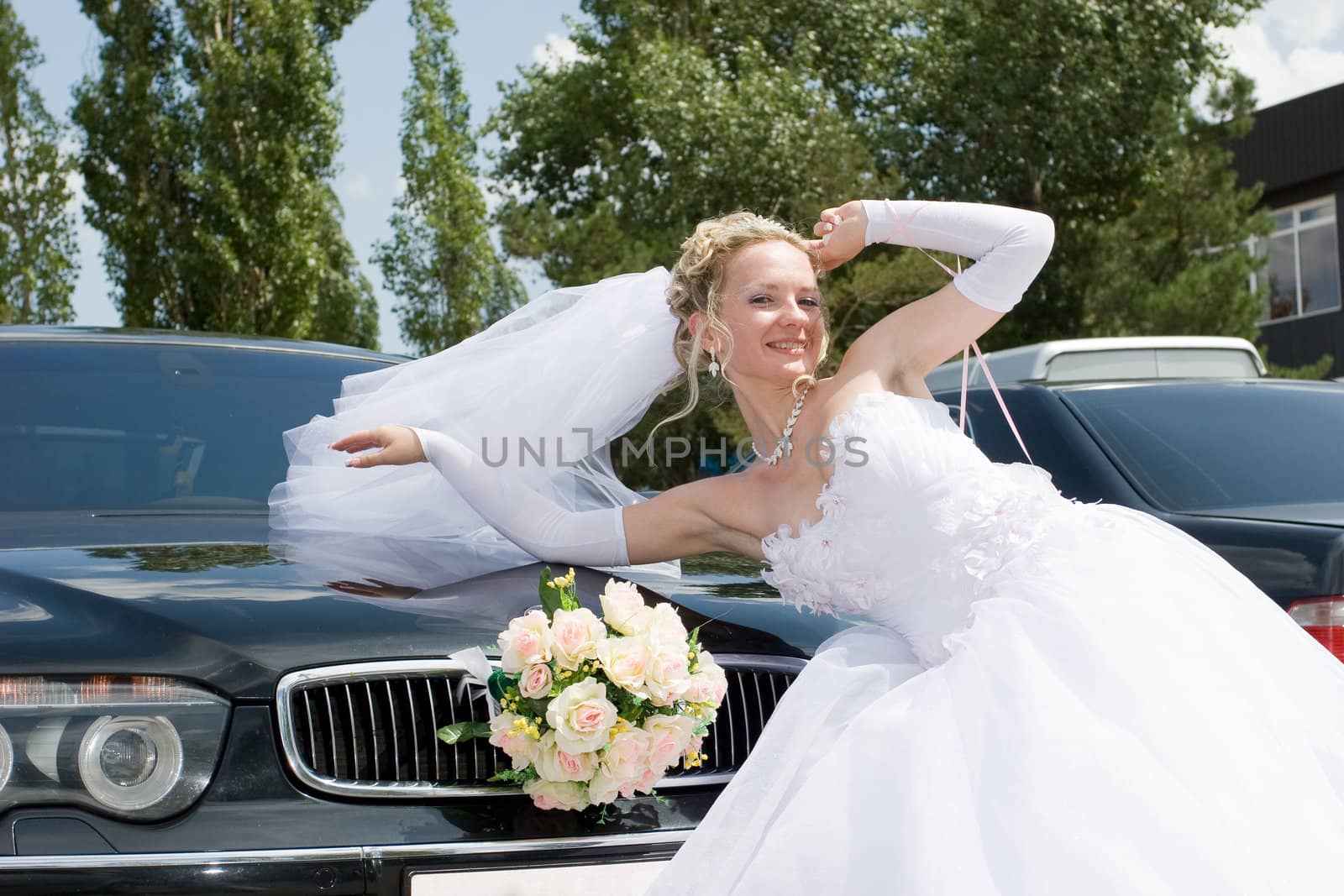 smiling bride near the decorated wedding car on a wind