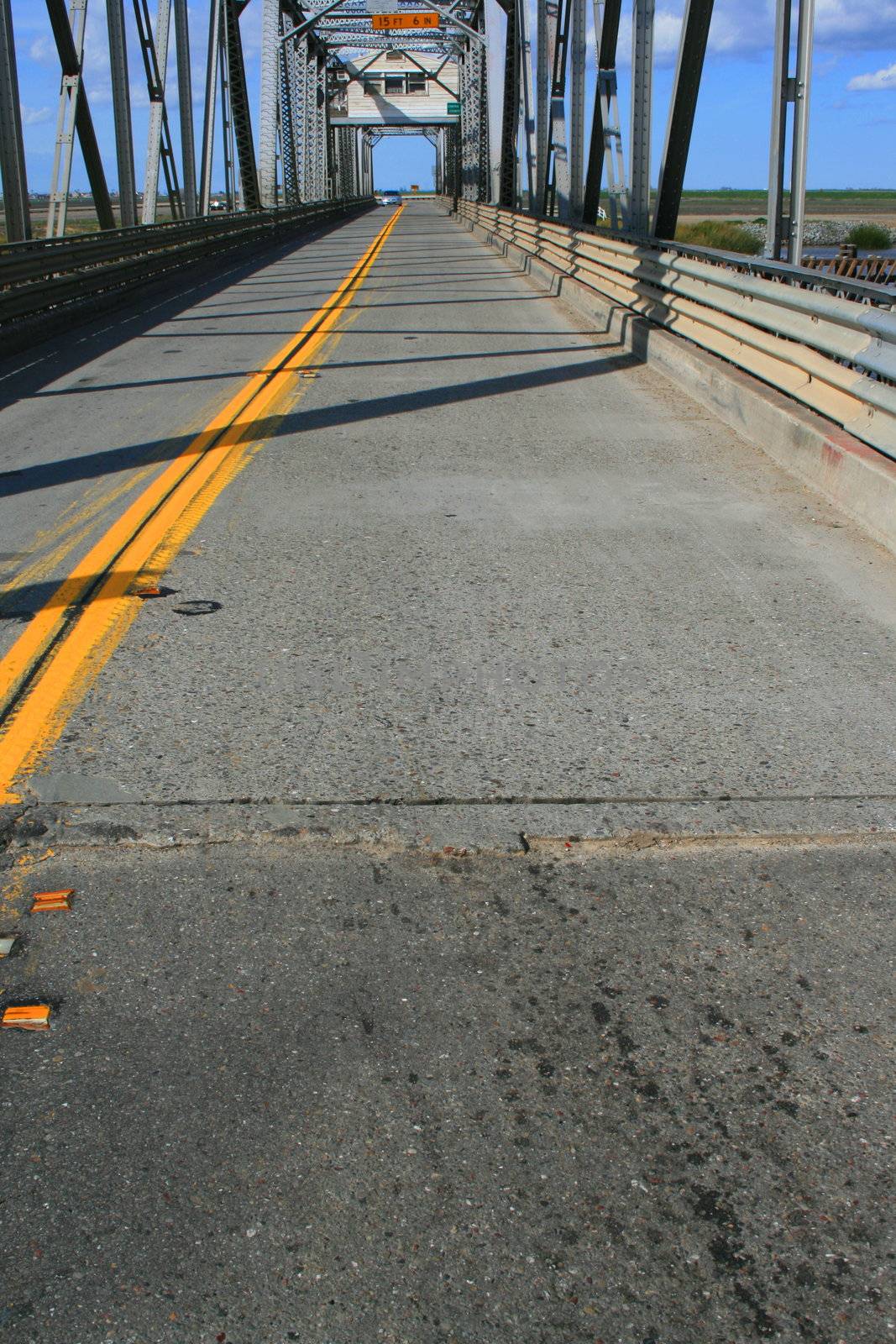 Two lane road on a bridge separated by yellow lines.
