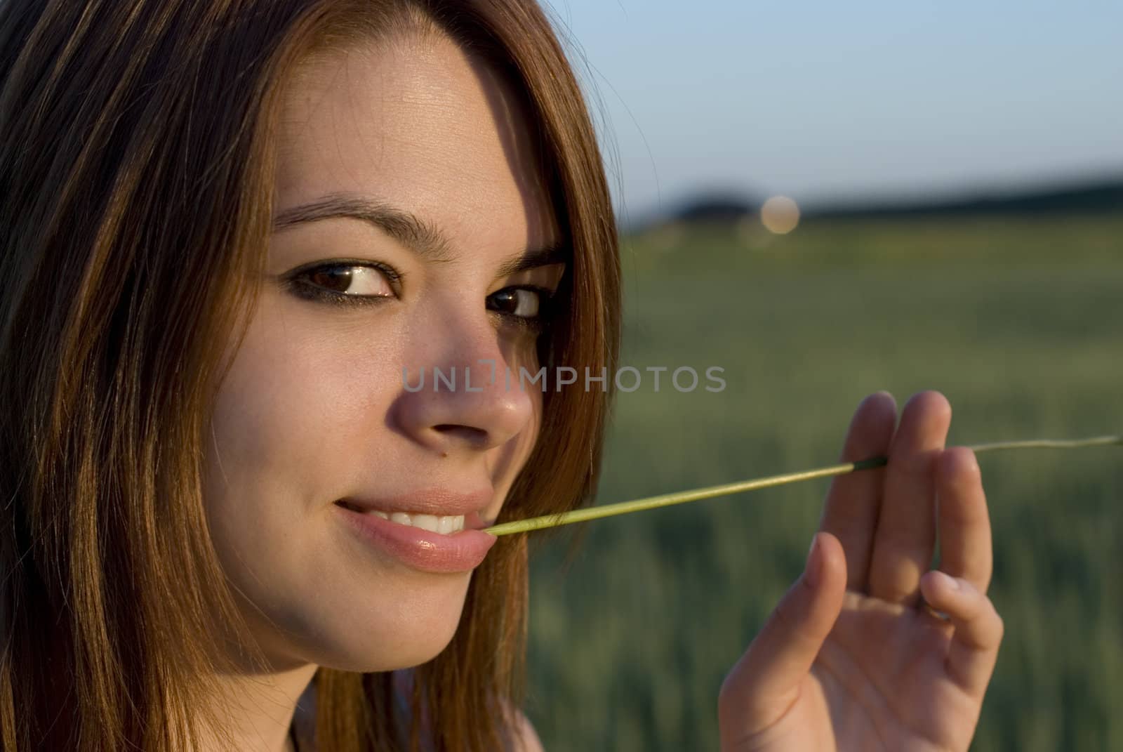 Portrait of young woman with straw in a field