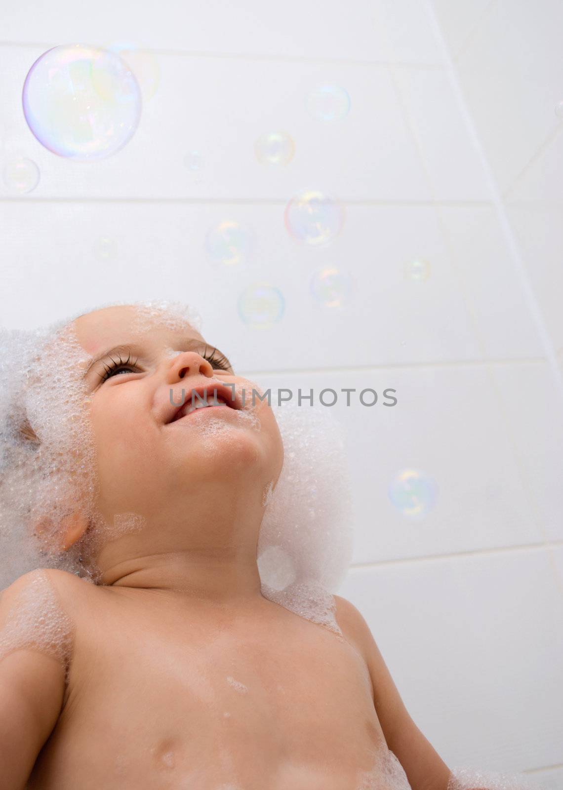 Little boy with foam on his head and bubbles