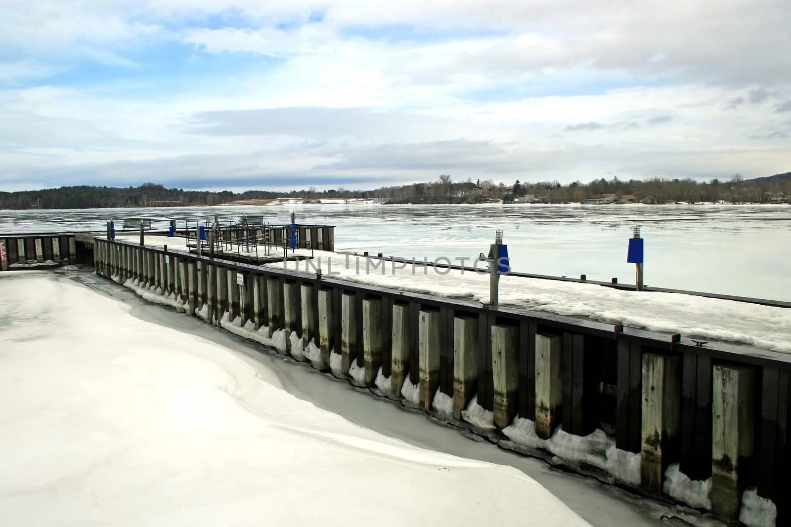 A dock and lake iced over in the winter