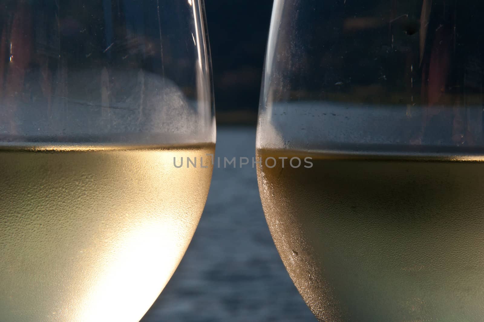 Closeup of two galsses filled with white wine with a lake in the background