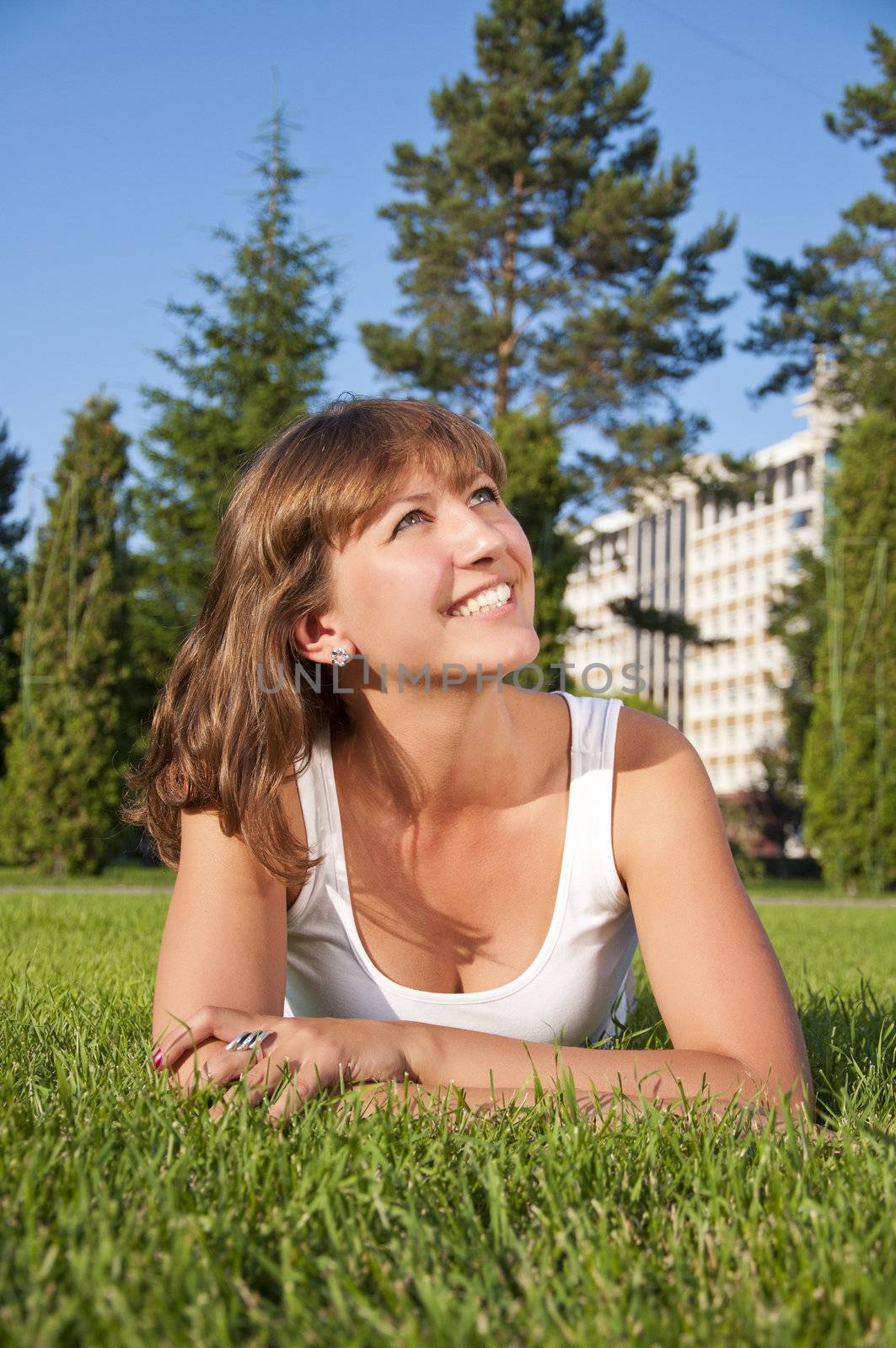 A very beautiful young woman lying down smiling in a field