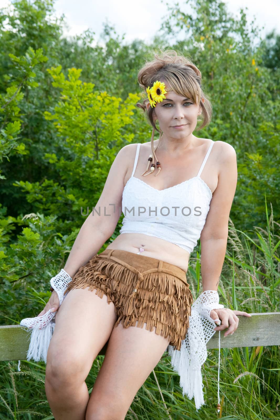 portrait of woman in shorts sitting on a fence in a rural setting