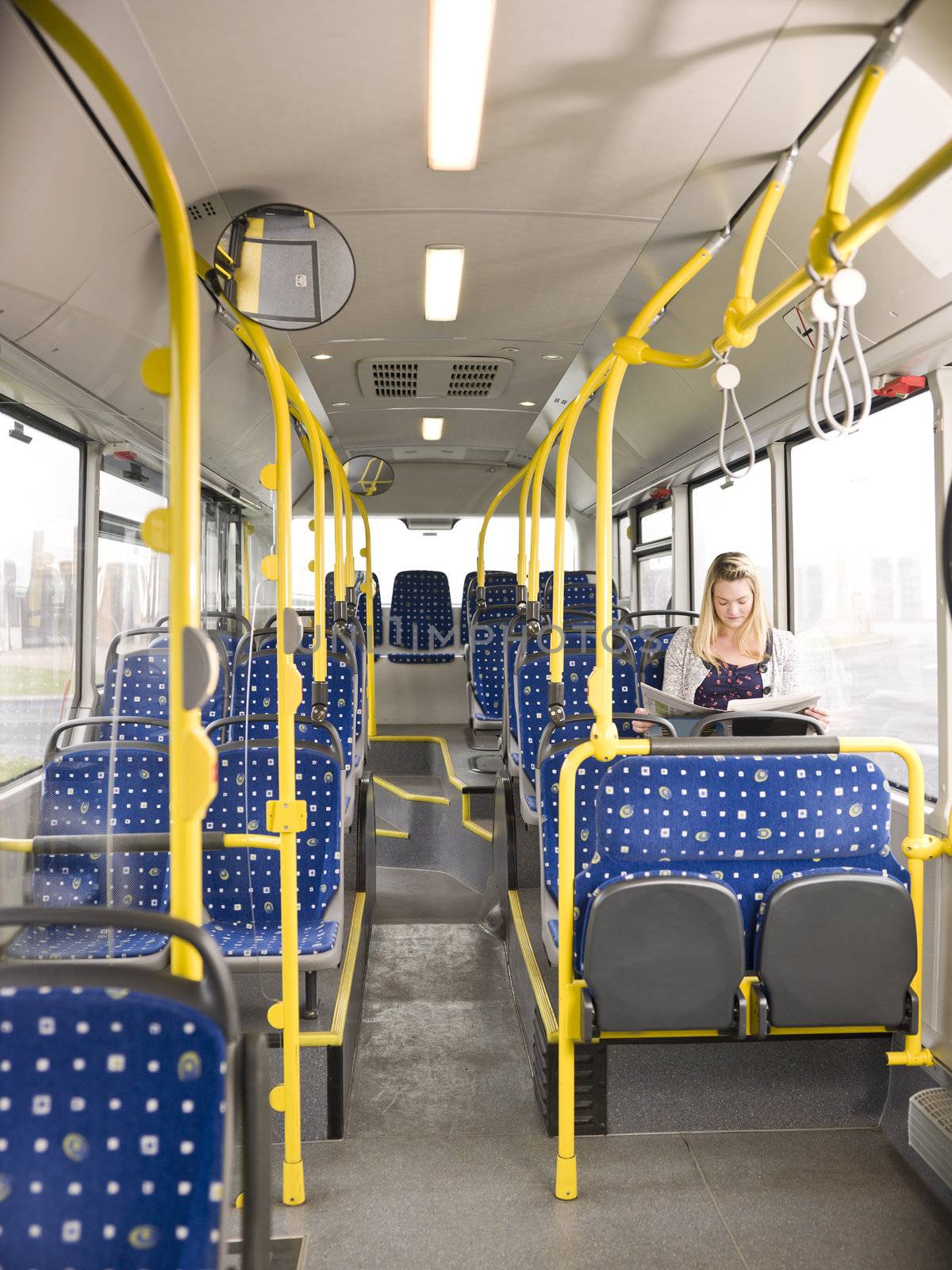 Lonely woman on the bus reading a newspaper