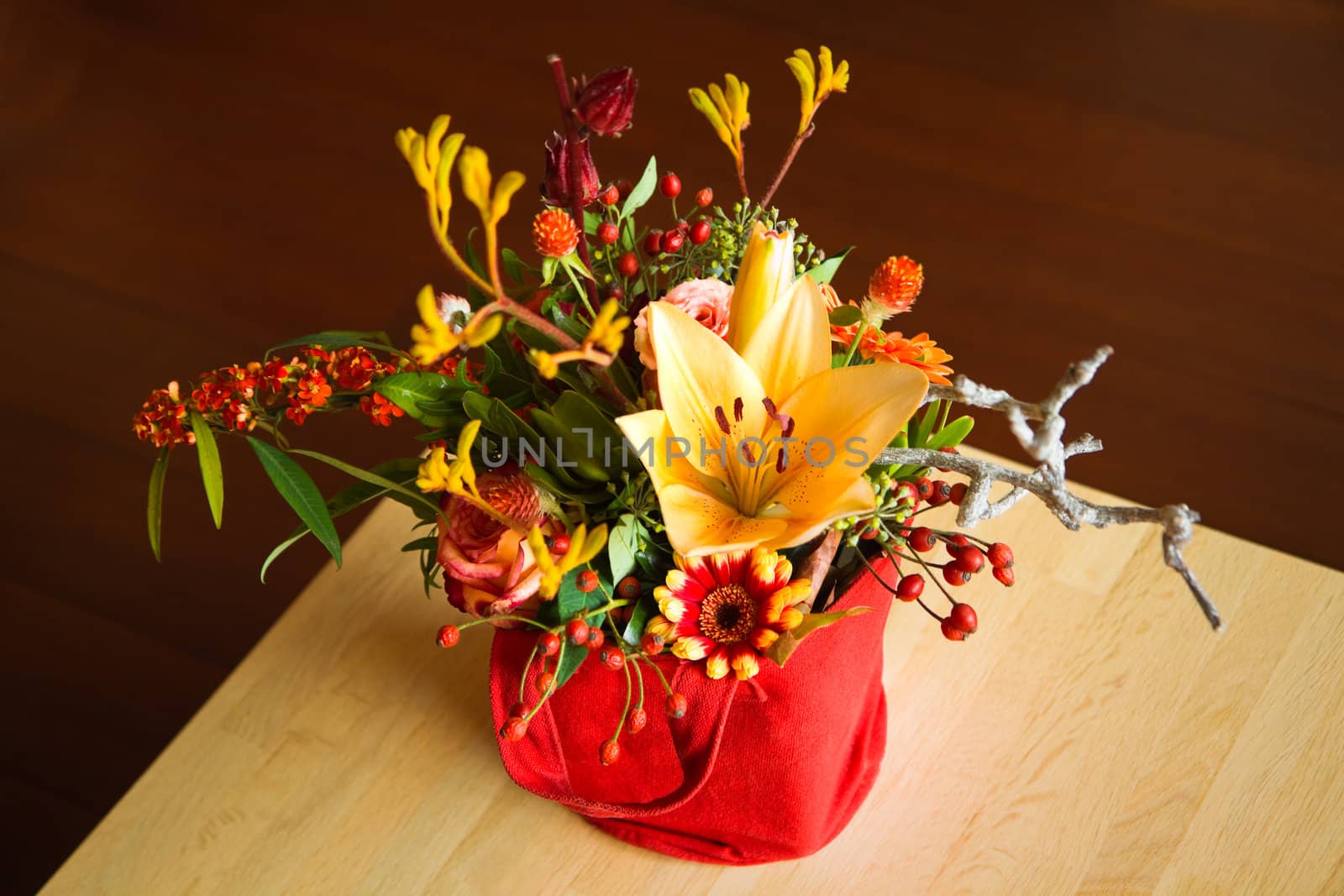 Mixed bouquet of yellow, red and orange flowers in beautiful little bag on a table