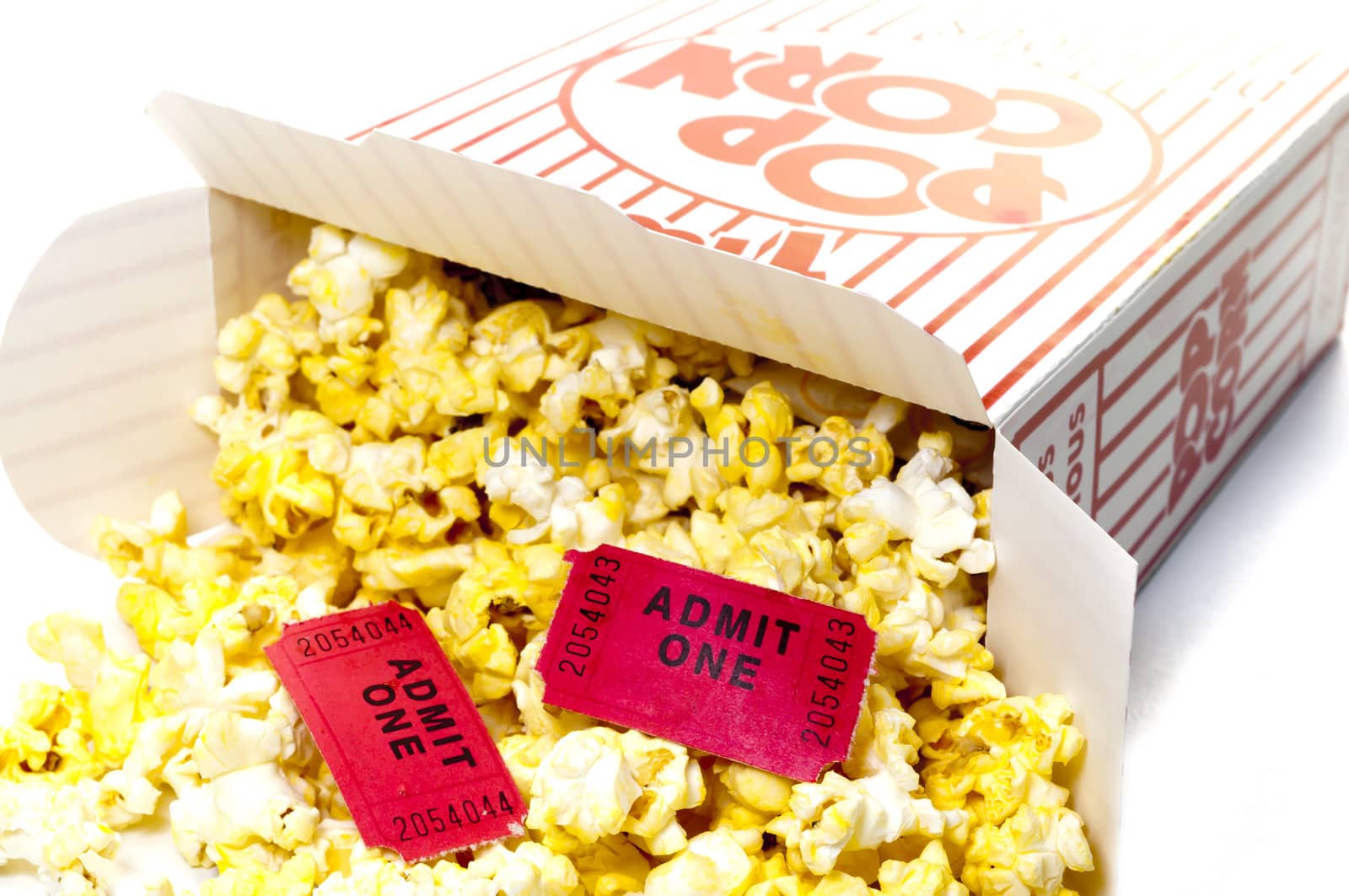 Closeup of box of popcorn on roll of movie tickets.  Isolated on white background.