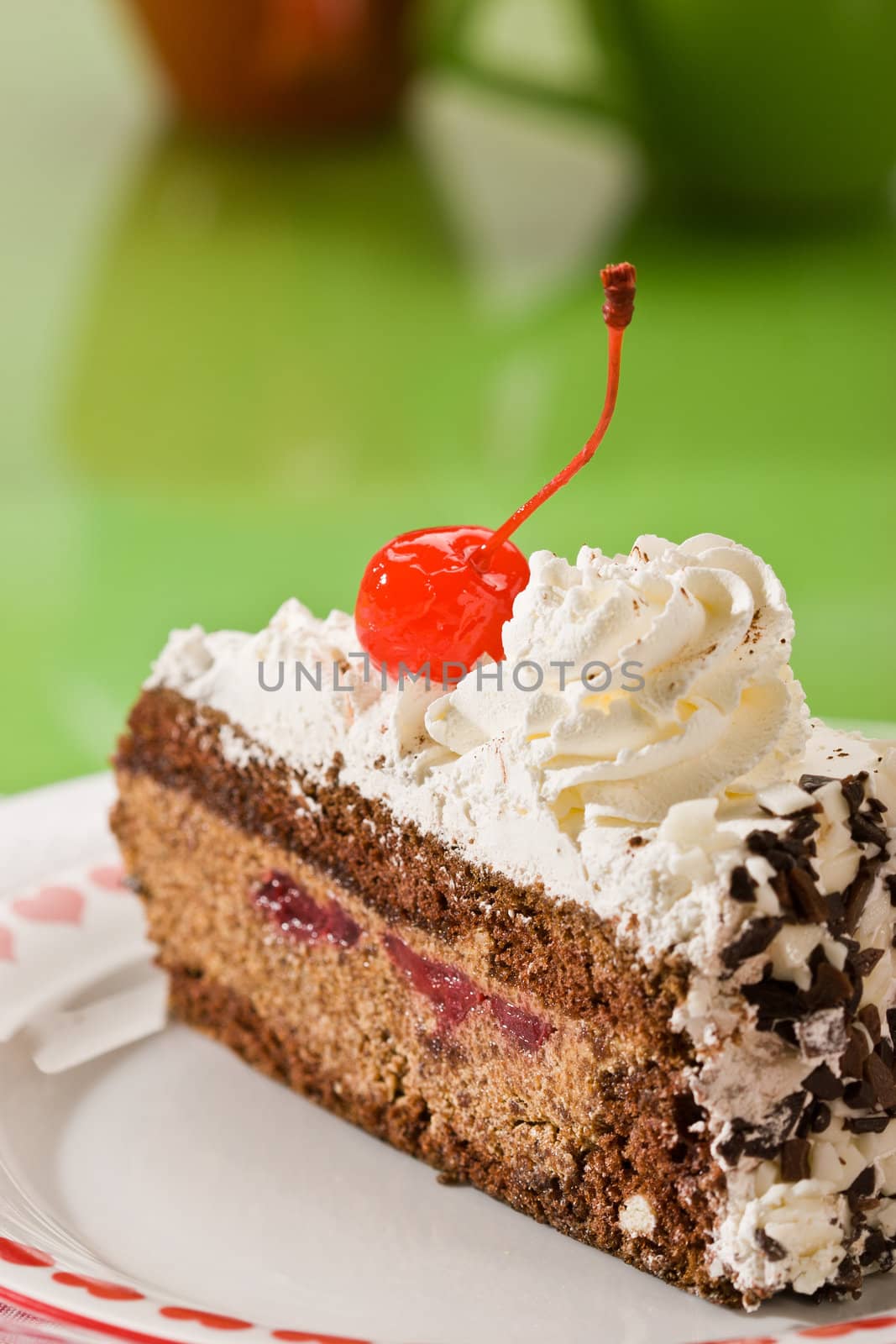 Slice of chocolate cake with cherry on the plate