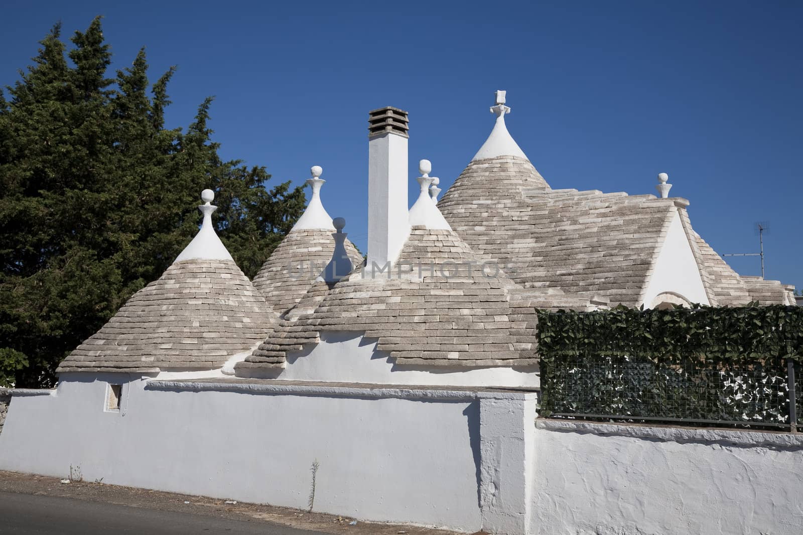 Modern rural trullo villa against a blue sky - Italy. A trullo is a traditional Apulian stone dwelling with a conical roof. The style of construction is specific to Itria Valley.