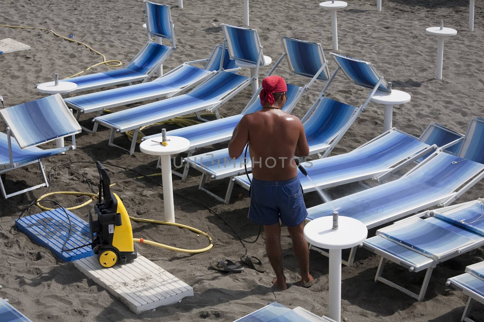 Hight pressure cleaning of sunbeds on Italian beach after end of the season.