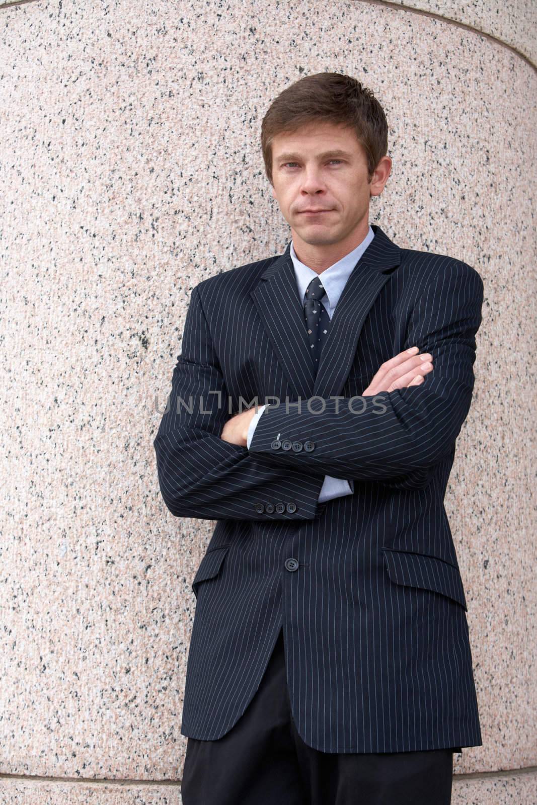 Man standing by pillar of building with arms crossed