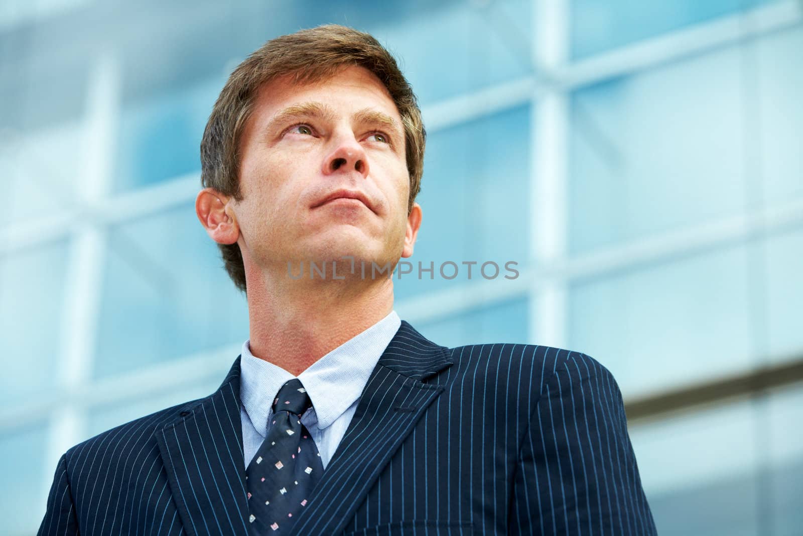 Man outside office building, looking up