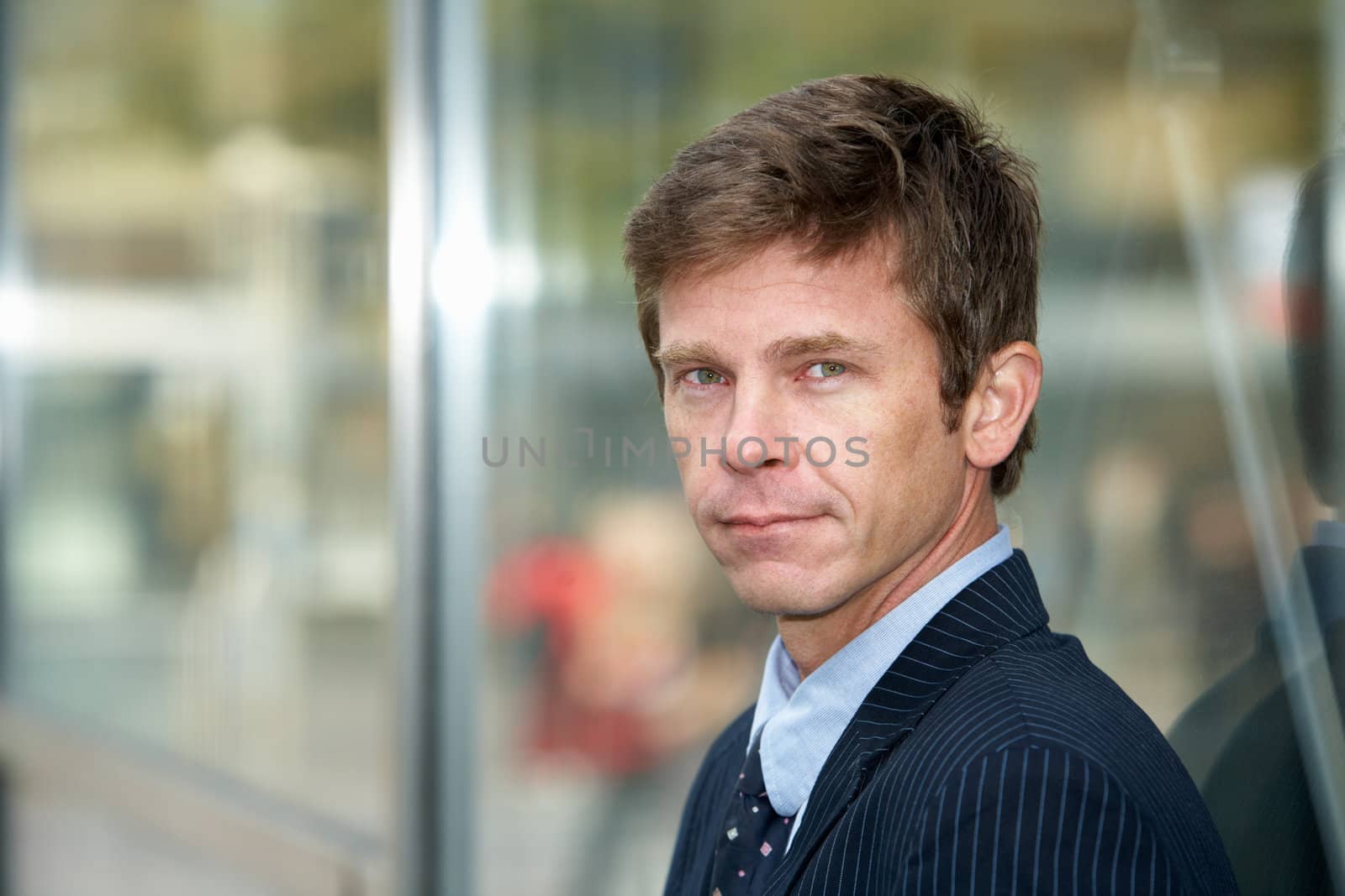 Man leaning against glass wall outdoors in city