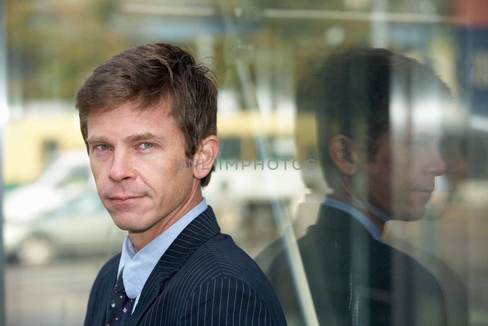 Man leaning against glass wall outdoors in city