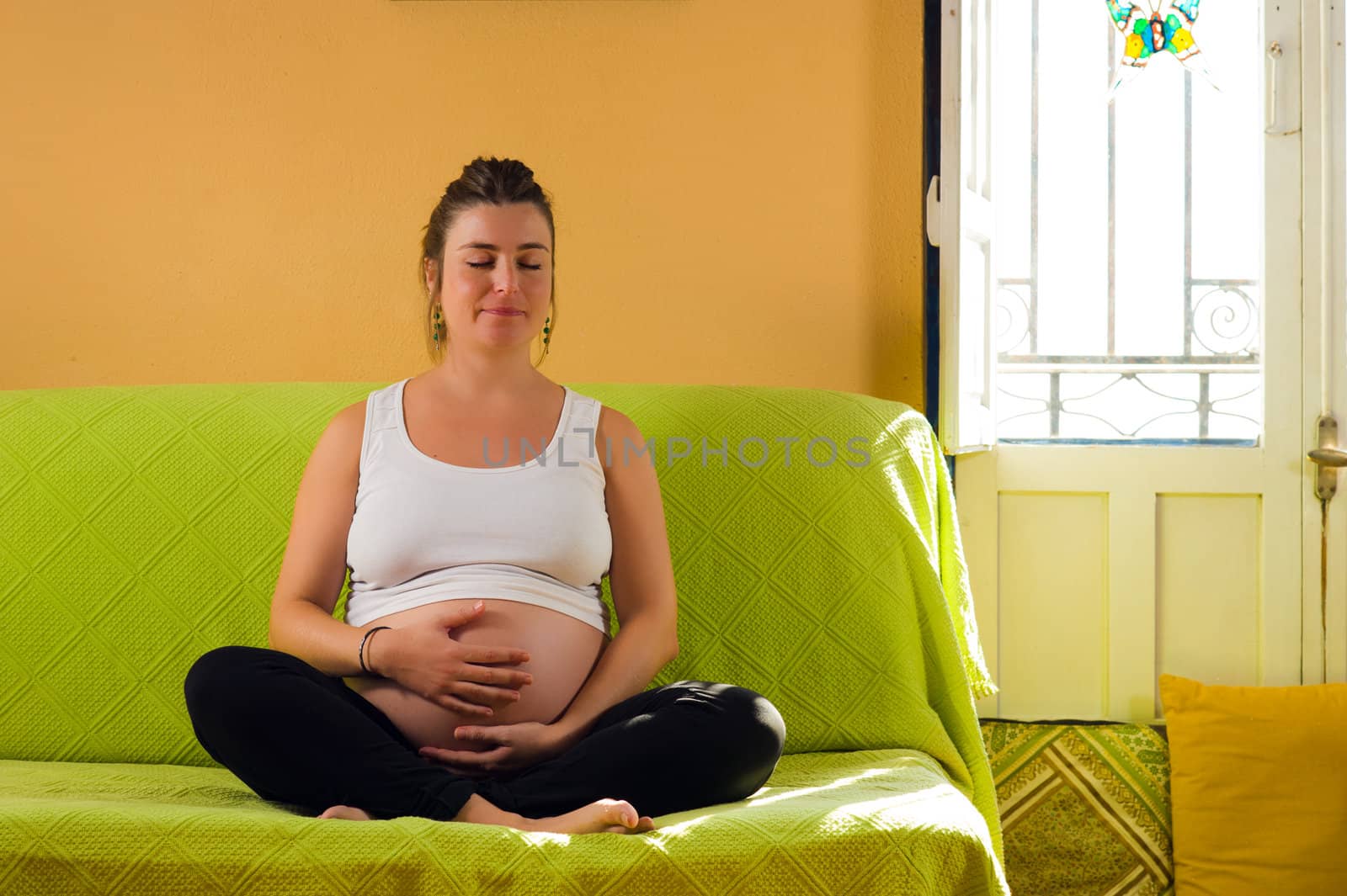 Pregnant woman meditating while sitting on a sofa