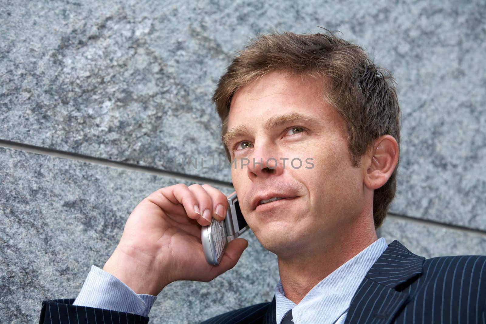 Man on cell phone by building wall, low angle close-up