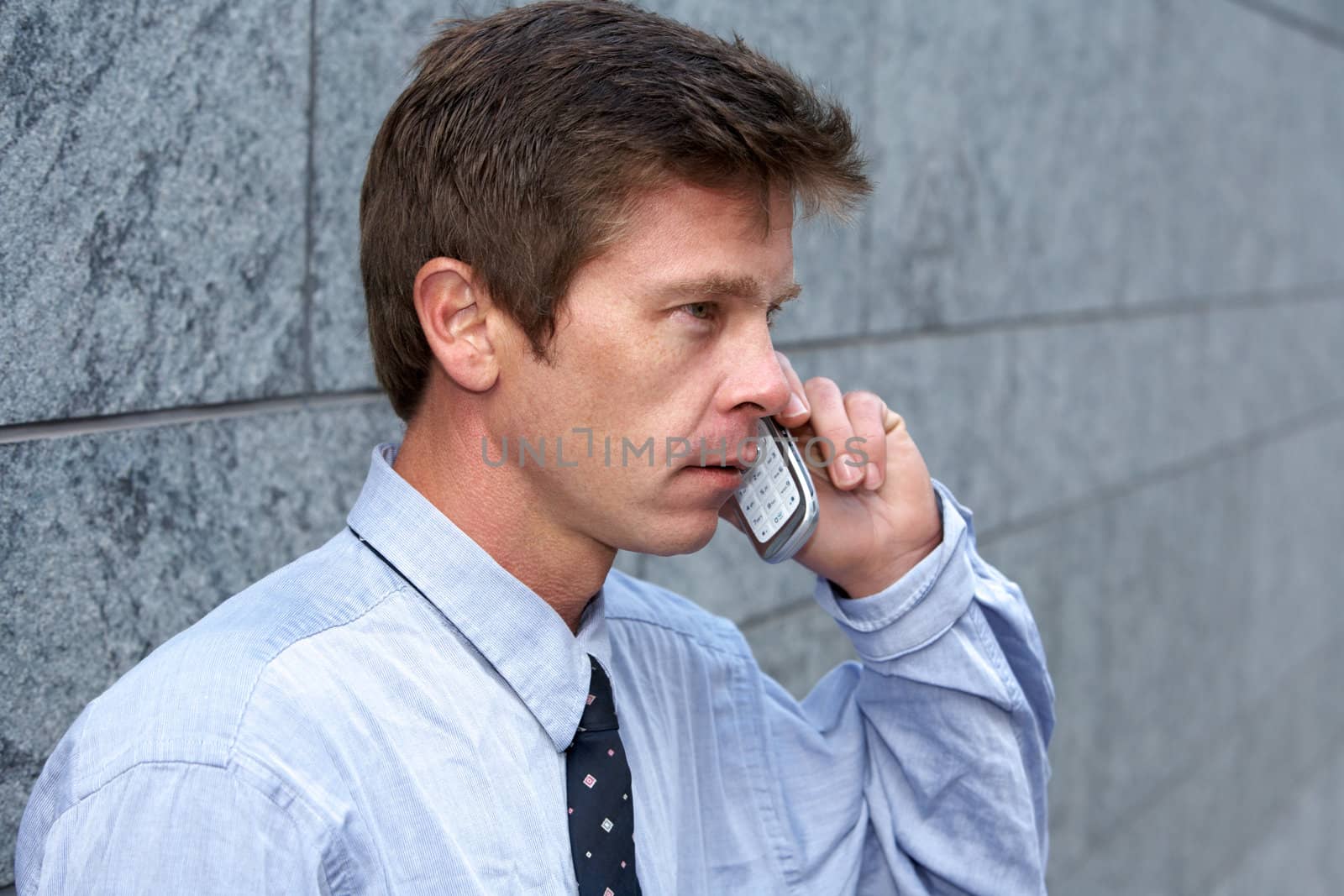 Man using cell phone by building wall