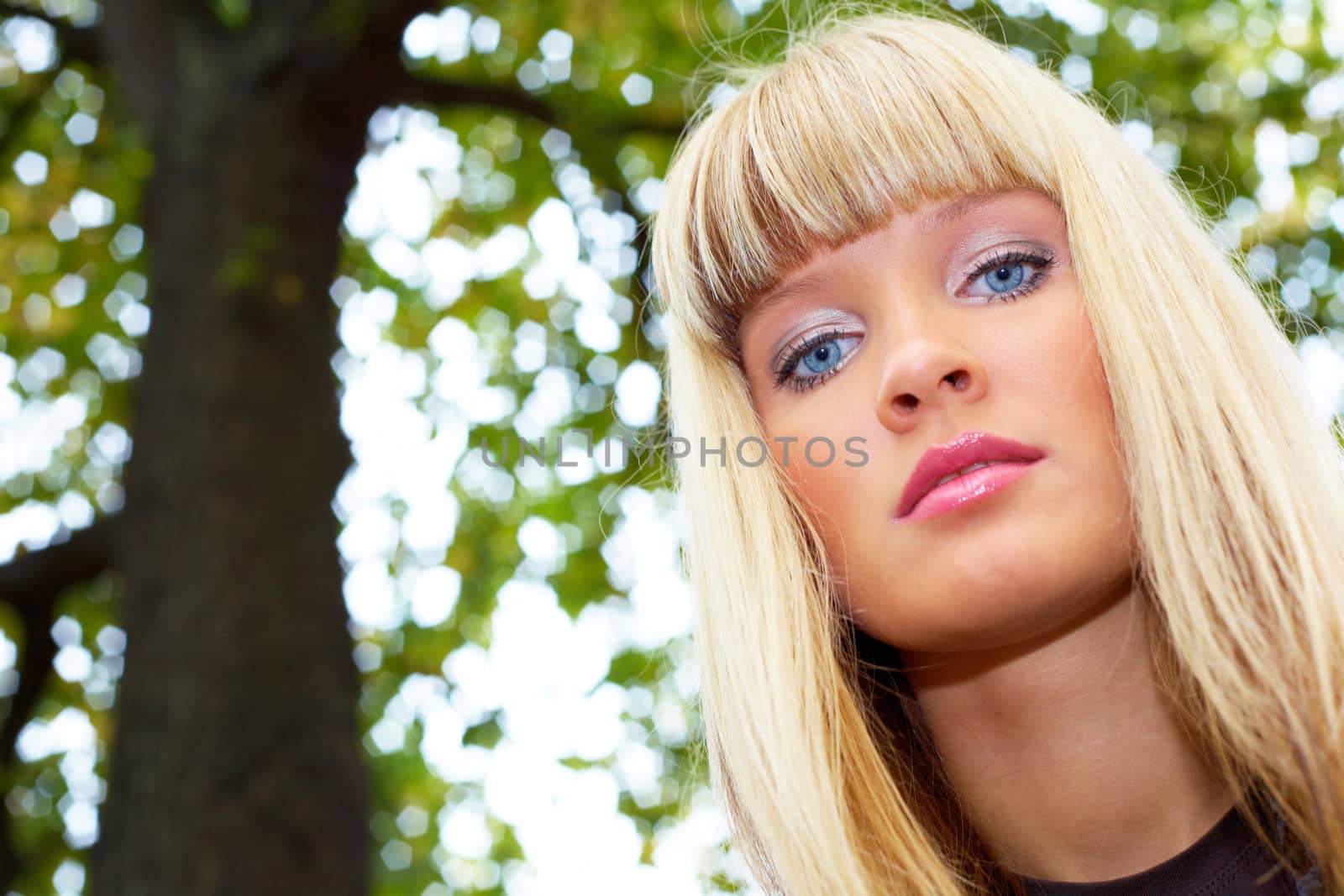 Low angle view of young woman by tree, looking at camera