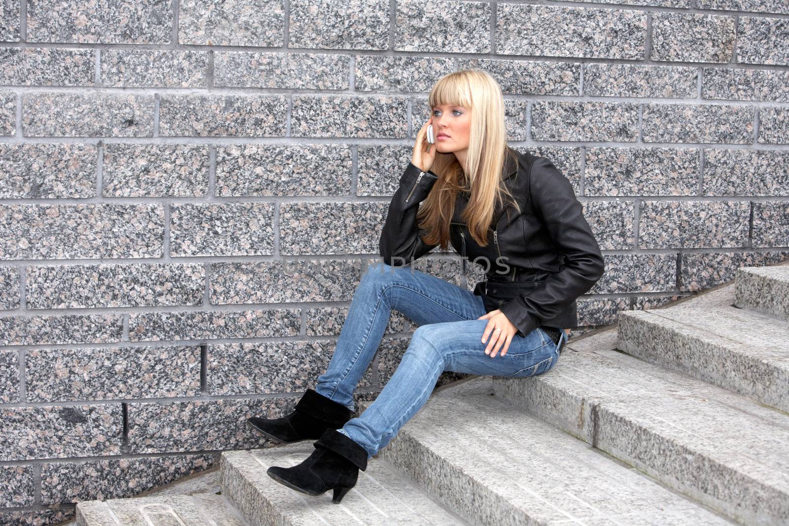 Young woman using mobile phone, sitting on stairway
