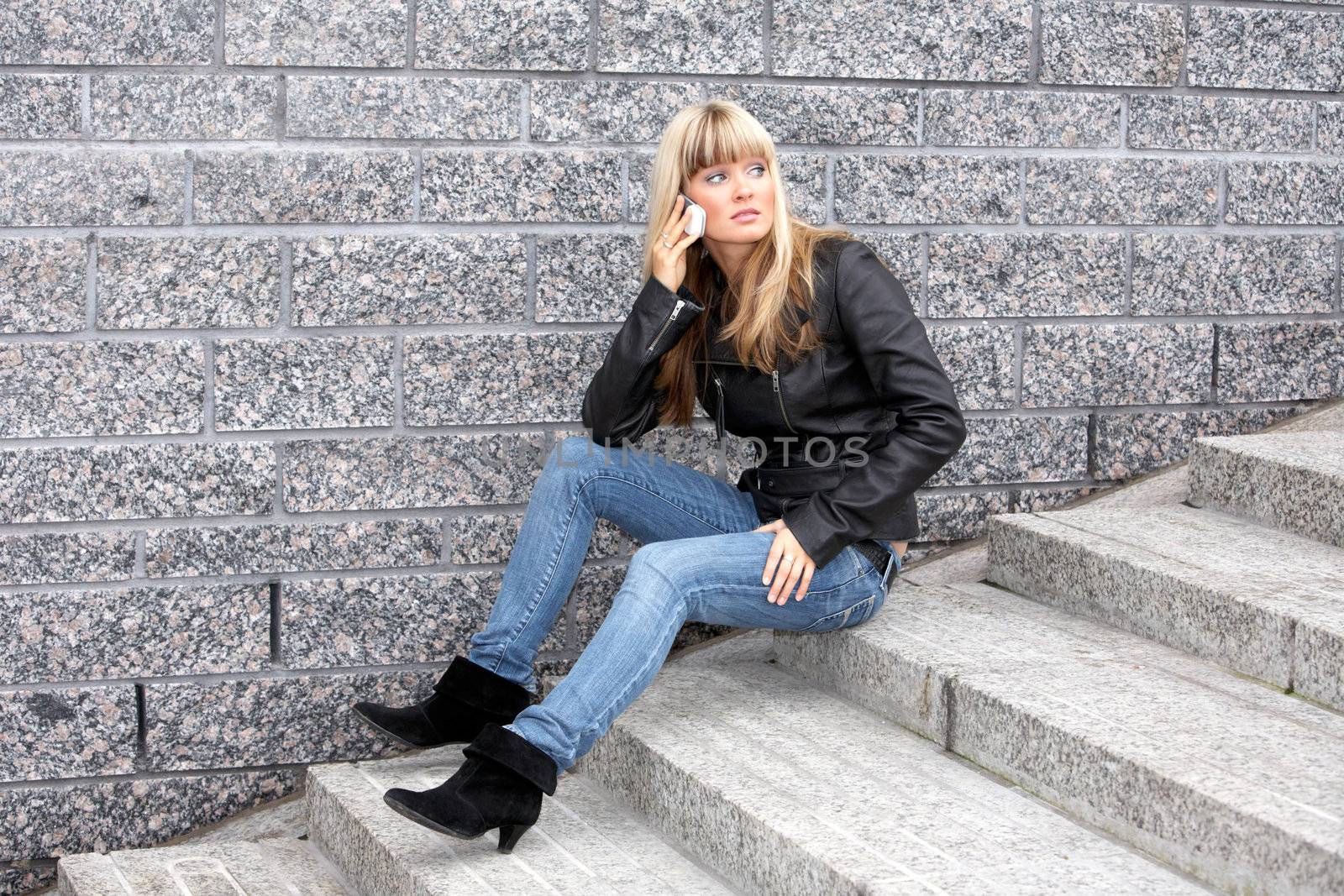 Young woman using mobile phone, sitting on stairway