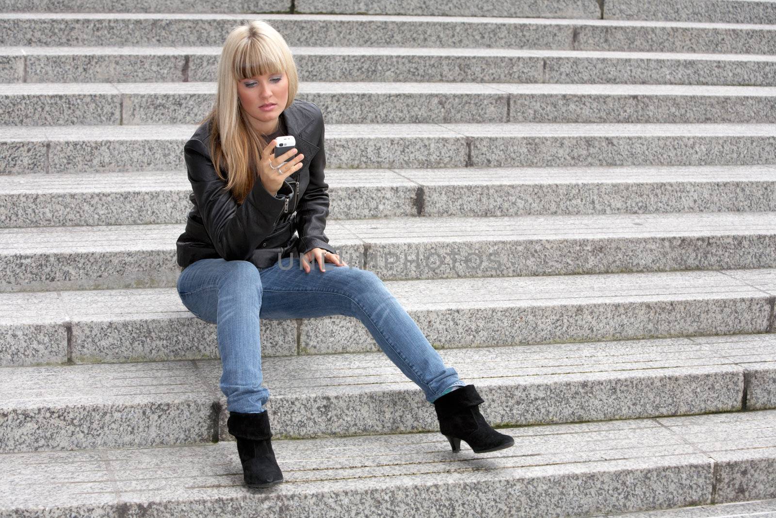 Young woman looking at mobile phone, sitting on stairway