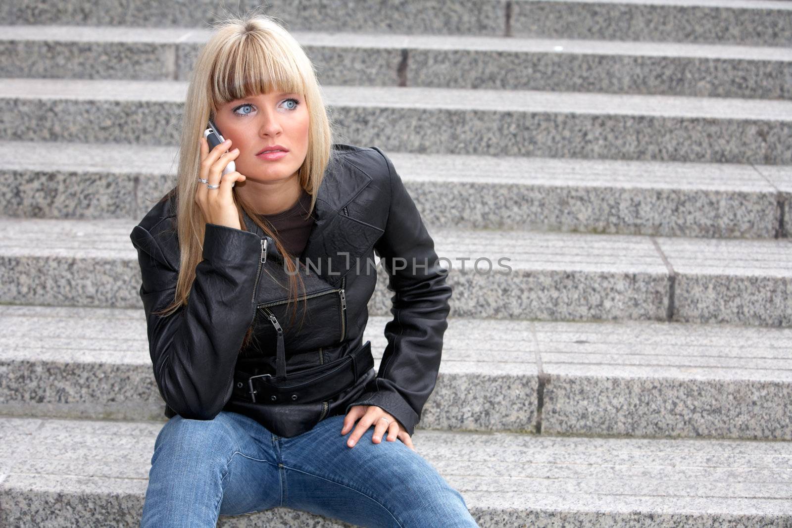 Young woman on mobile phone, looking away, sitting on stairway