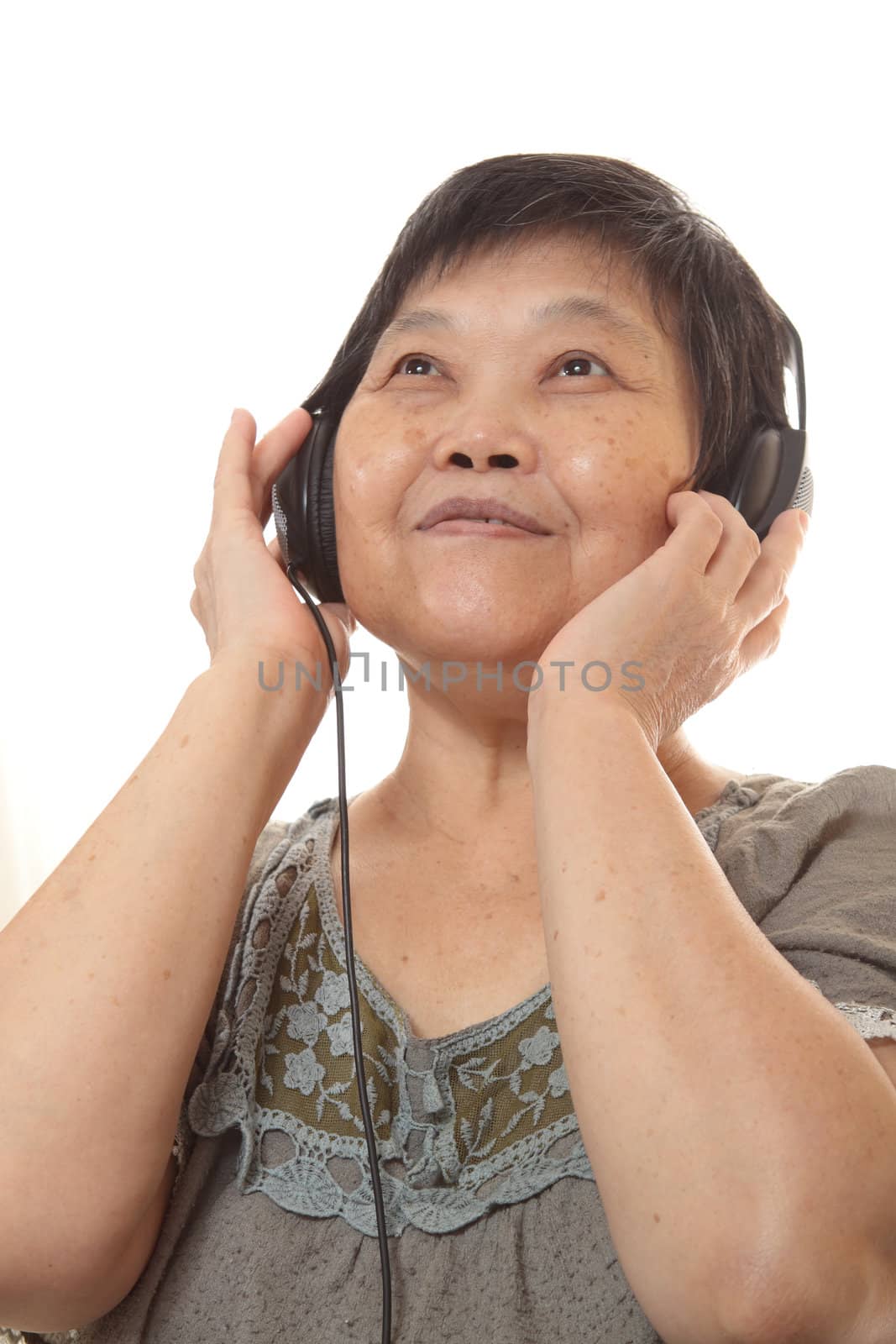 Senior woman listening to music with headphones  by cozyta