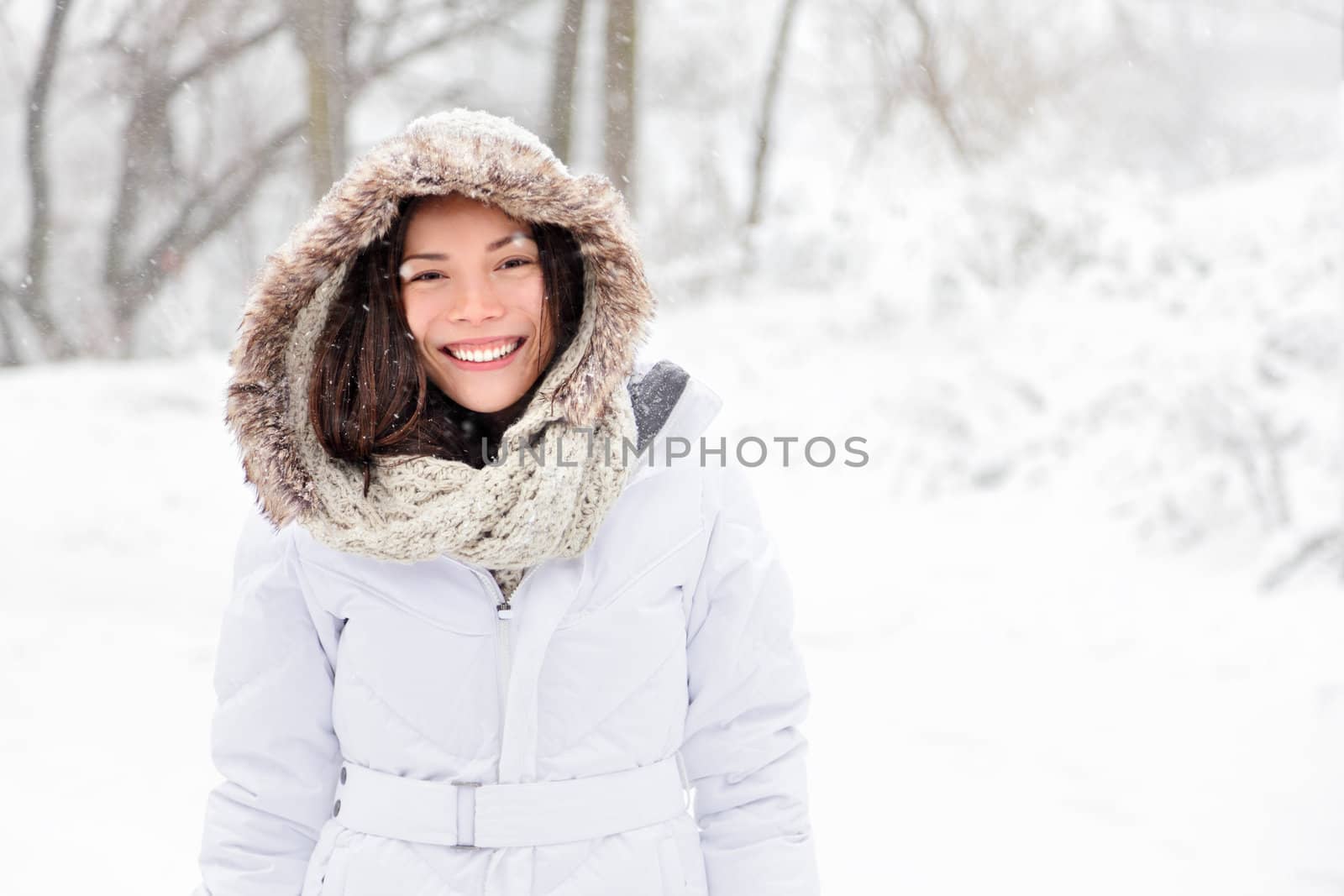 Snow winter woman portrait outdoors on snowy white winter day. Beautiful asian girl smiling happy outside.