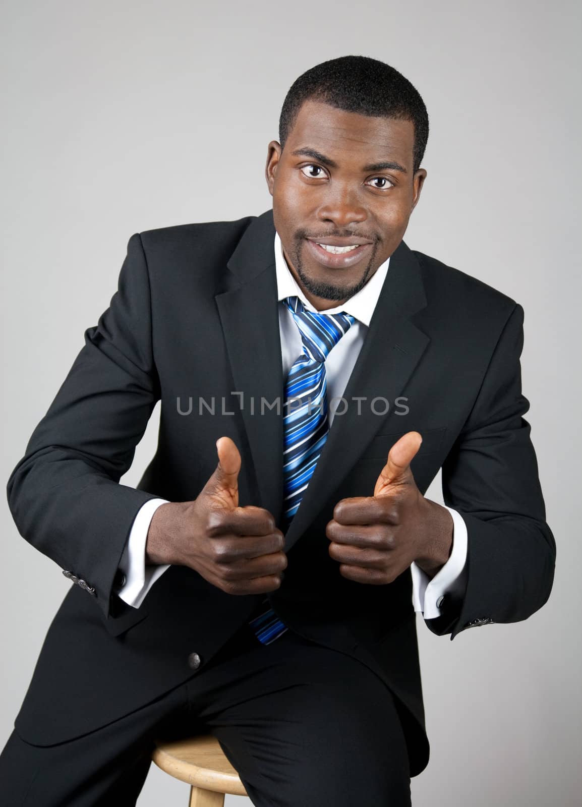 Smiling successful African American businessman with thumbs up.
