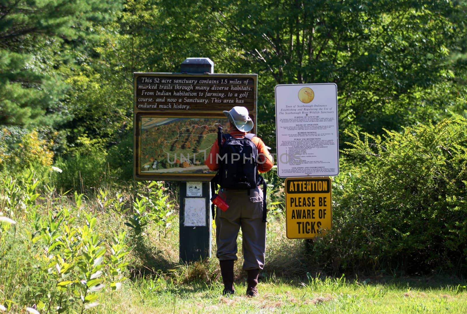 Hiker seeking information from a board on a pathway